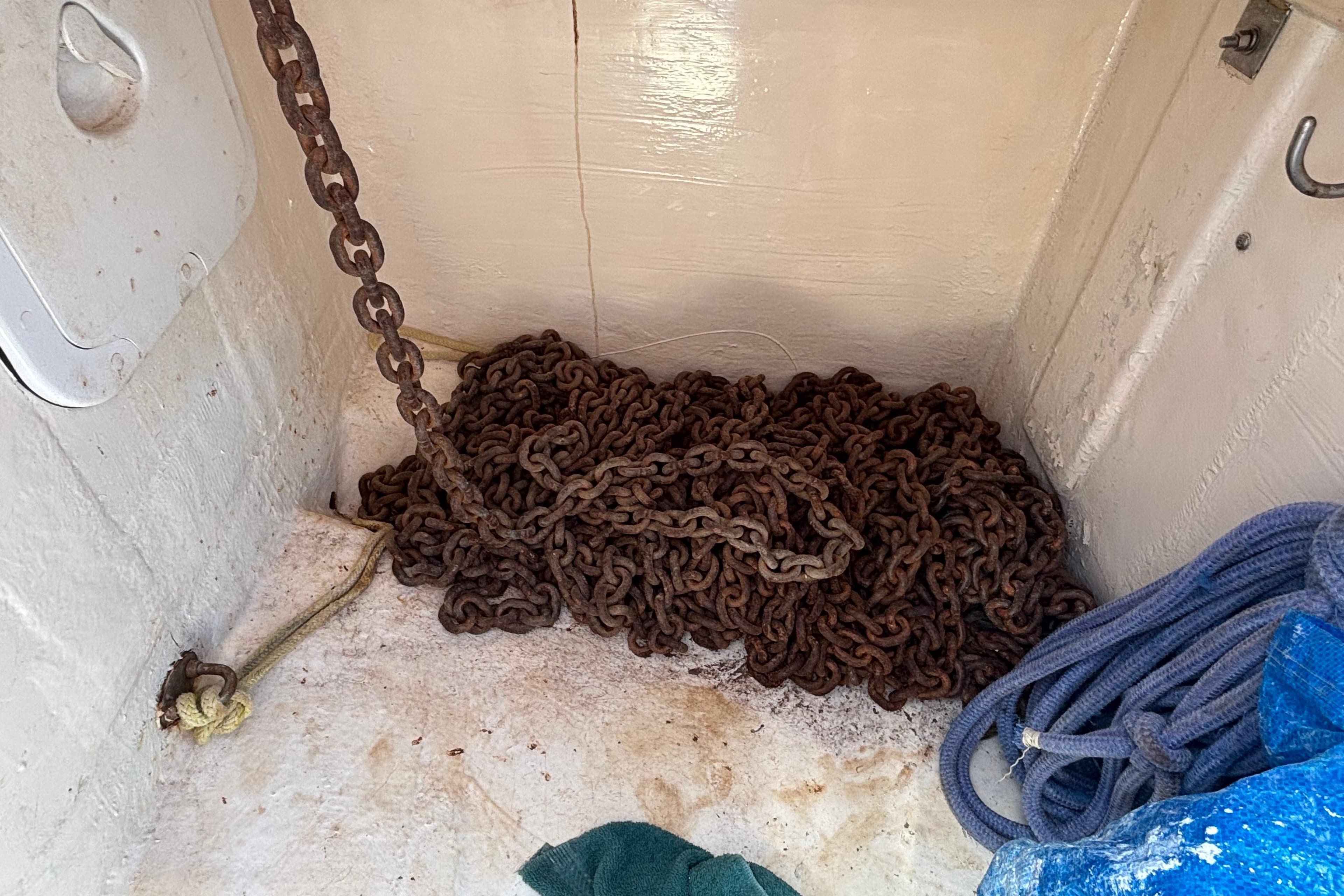 Rusty anchor chain and blue rope in a 1998 Prout 38 boat compartment.