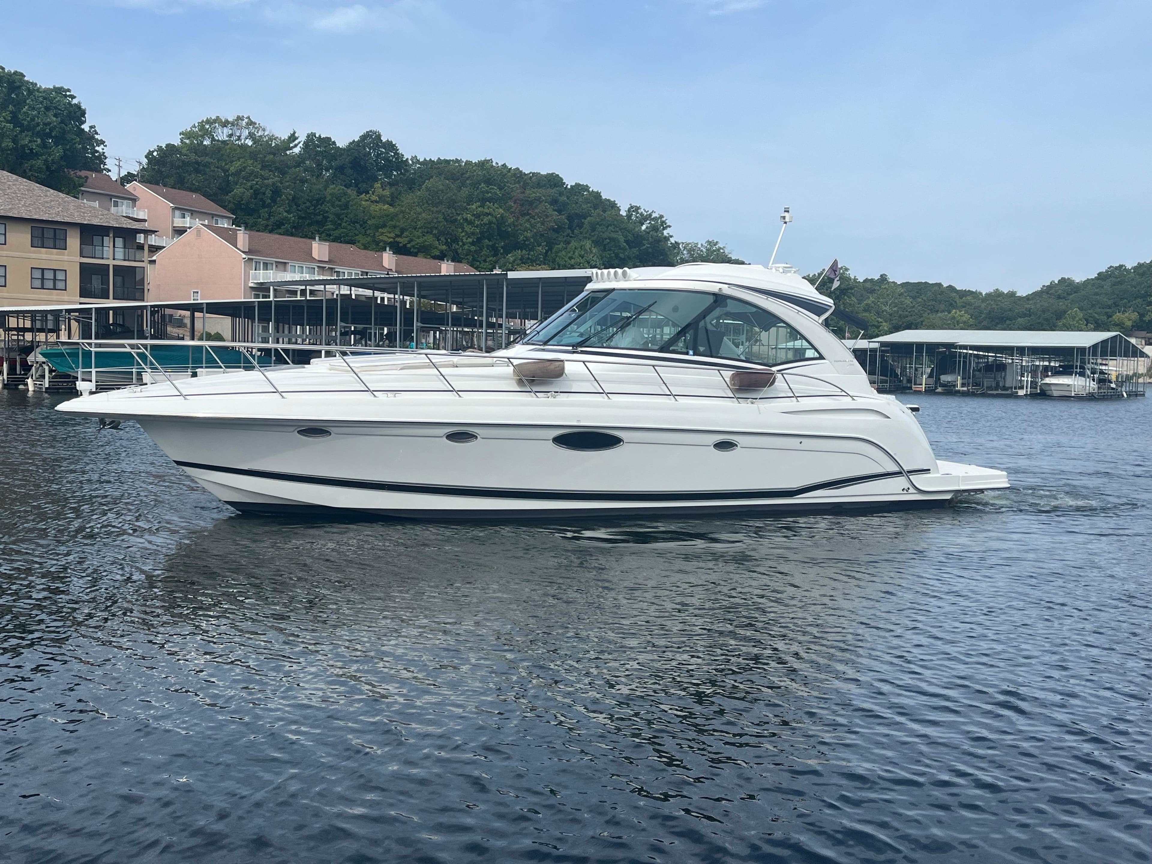 2014 Formula 45 Yacht cruising on a serene lake near docks and trees.