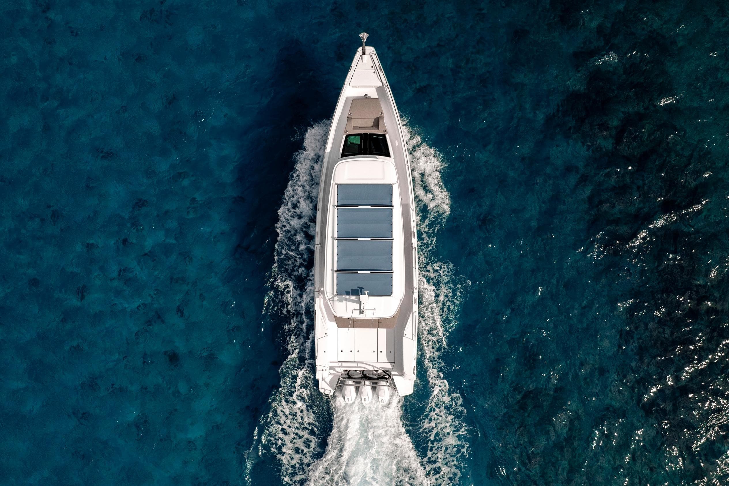 Aerial view of 2025 Axopar 45 Cross Top boat cruising on clear blue water.