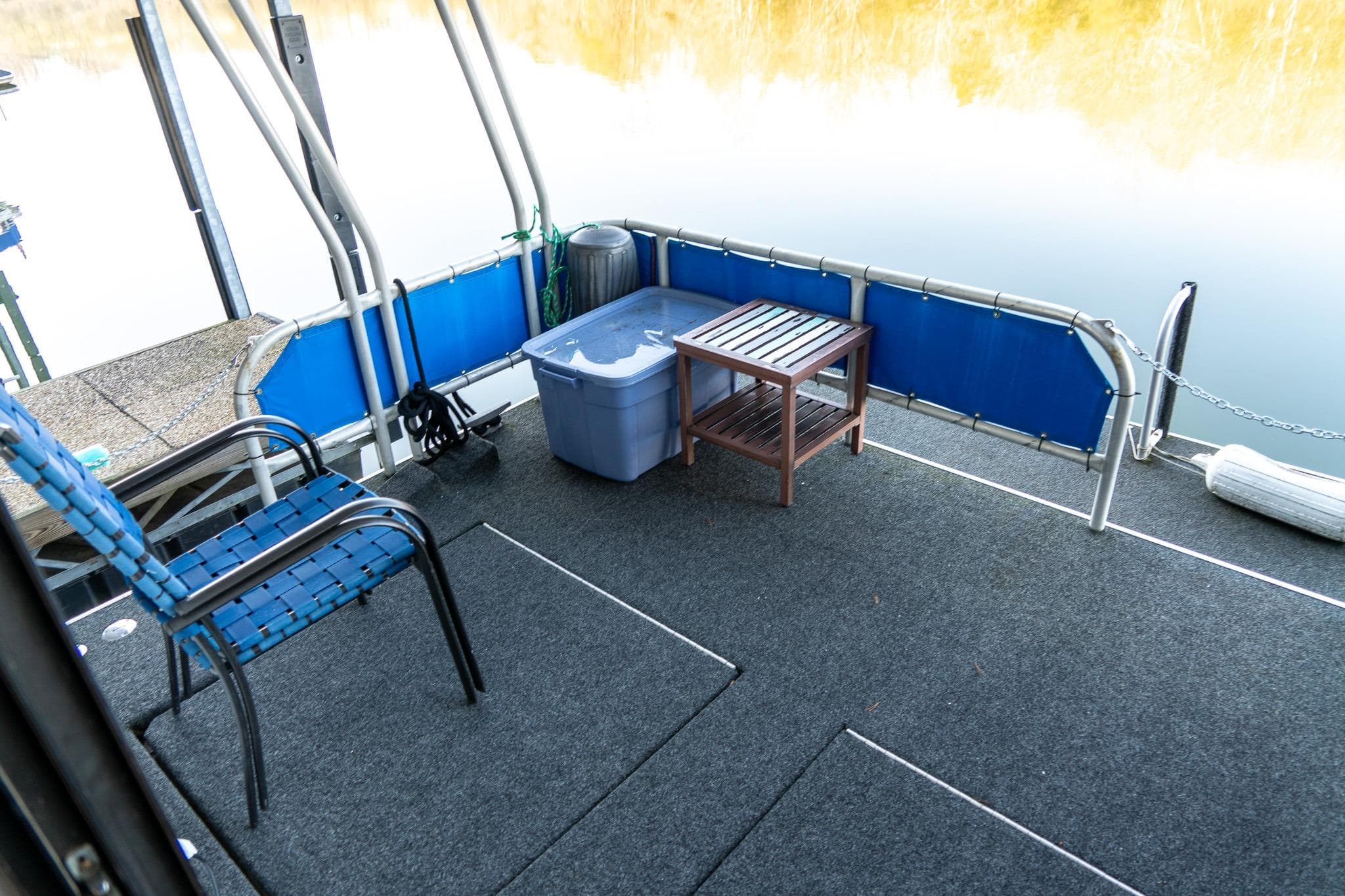 Houseboat deck with chairs, table, and storage bin on calm water. Lakeview 66 x 16 Widebody, 1996.