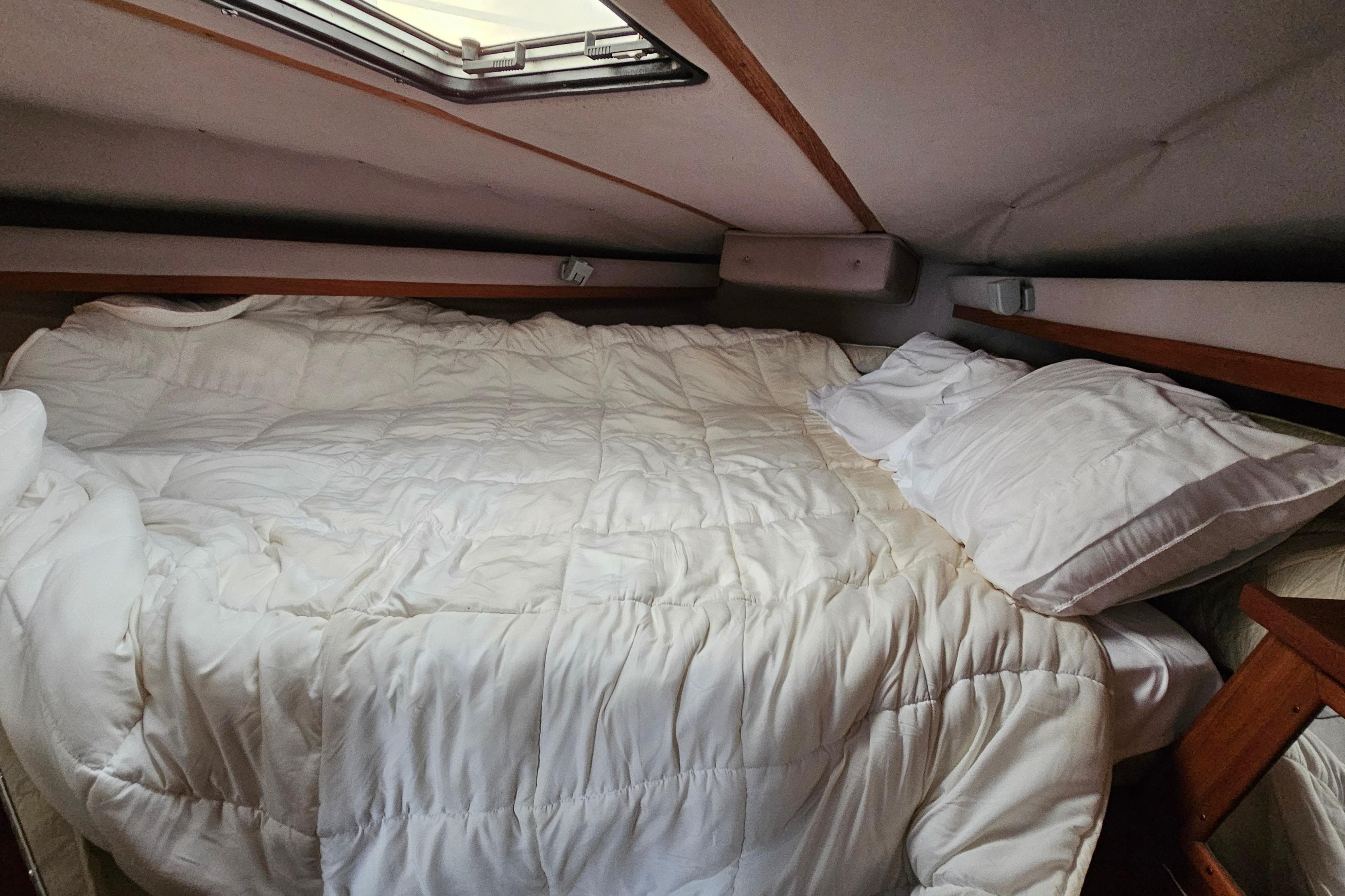 Cozy cabin bed in 1988 Regal Commodore 360 yacht with white bedding.