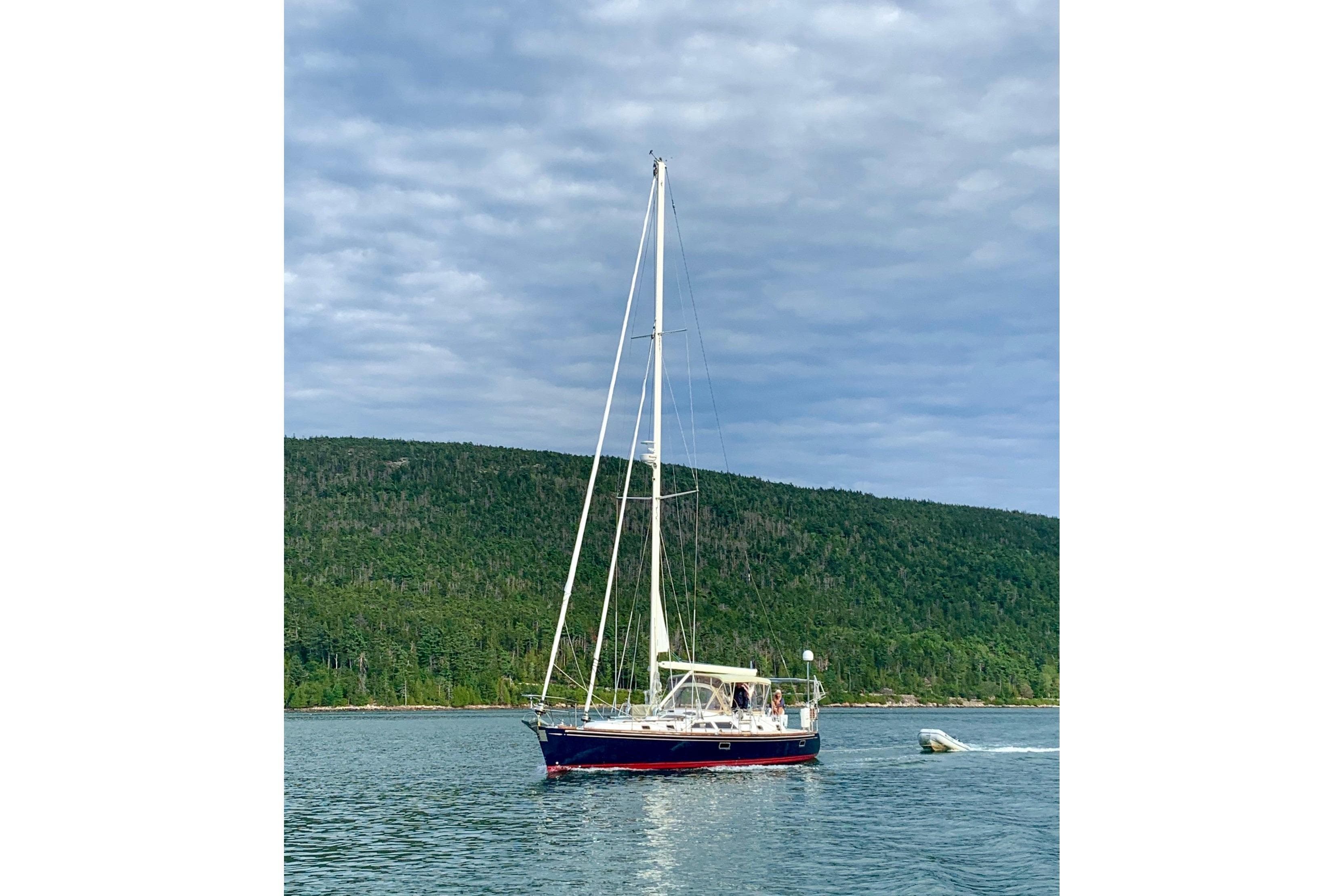Sailing yacht Hylas 46 (2002) cruising on a serene lake with forested hills.