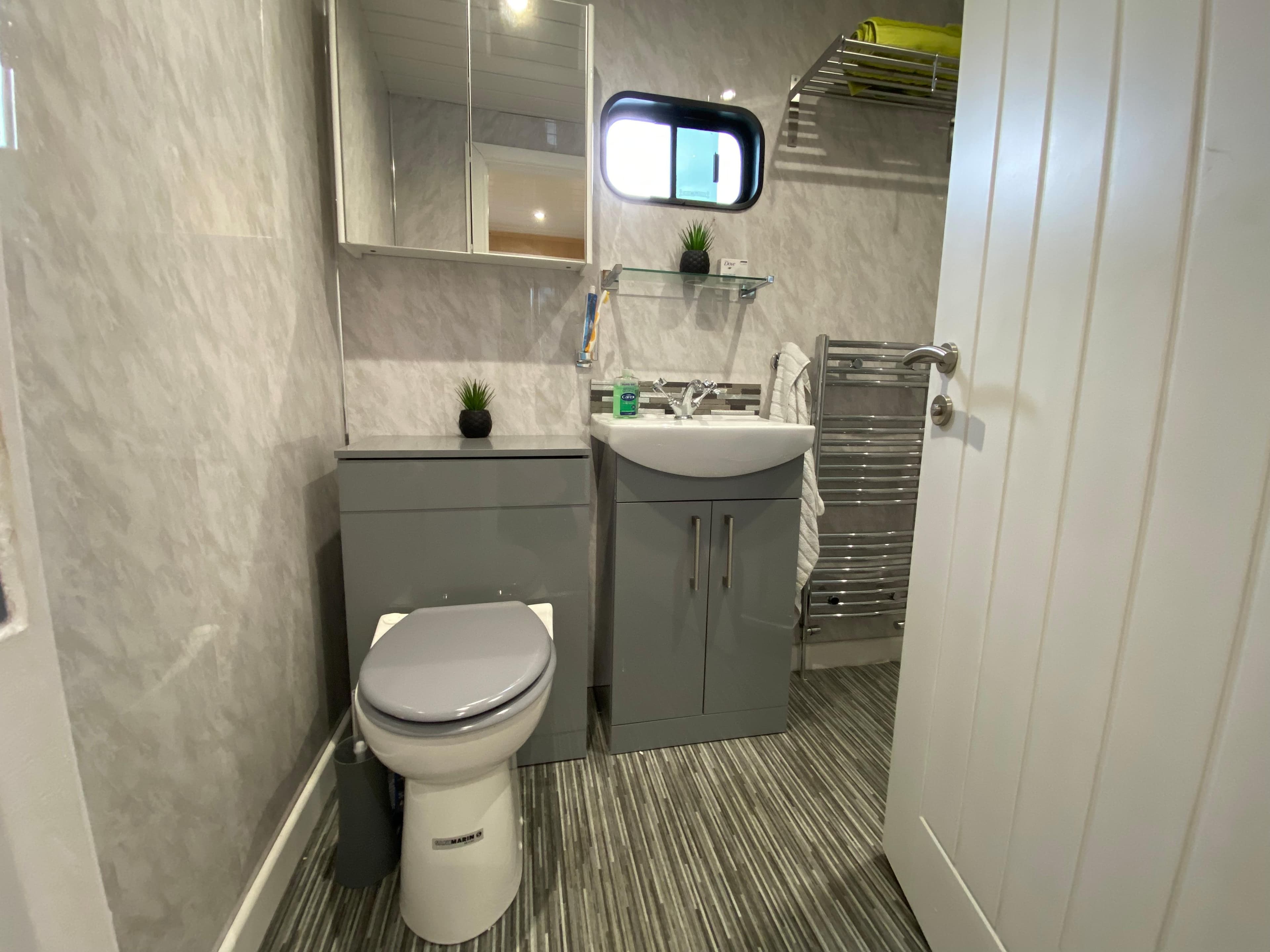 Modern bathroom interior on 2002 Widebeam Barge with sleek fixtures and striped flooring.