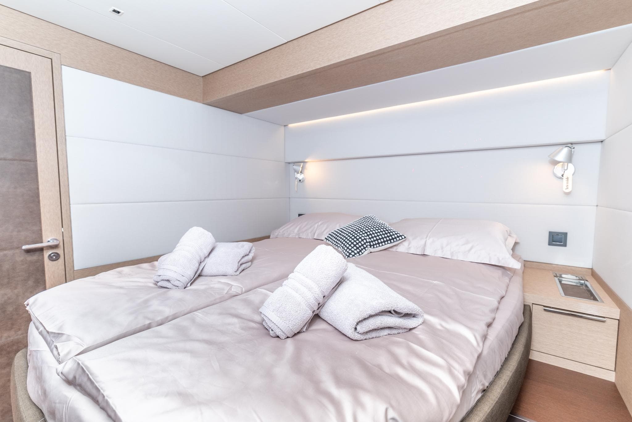 Luxurious bedroom interior of 2024 Lagoon SIXTY 5 yacht with neatly arranged towels.