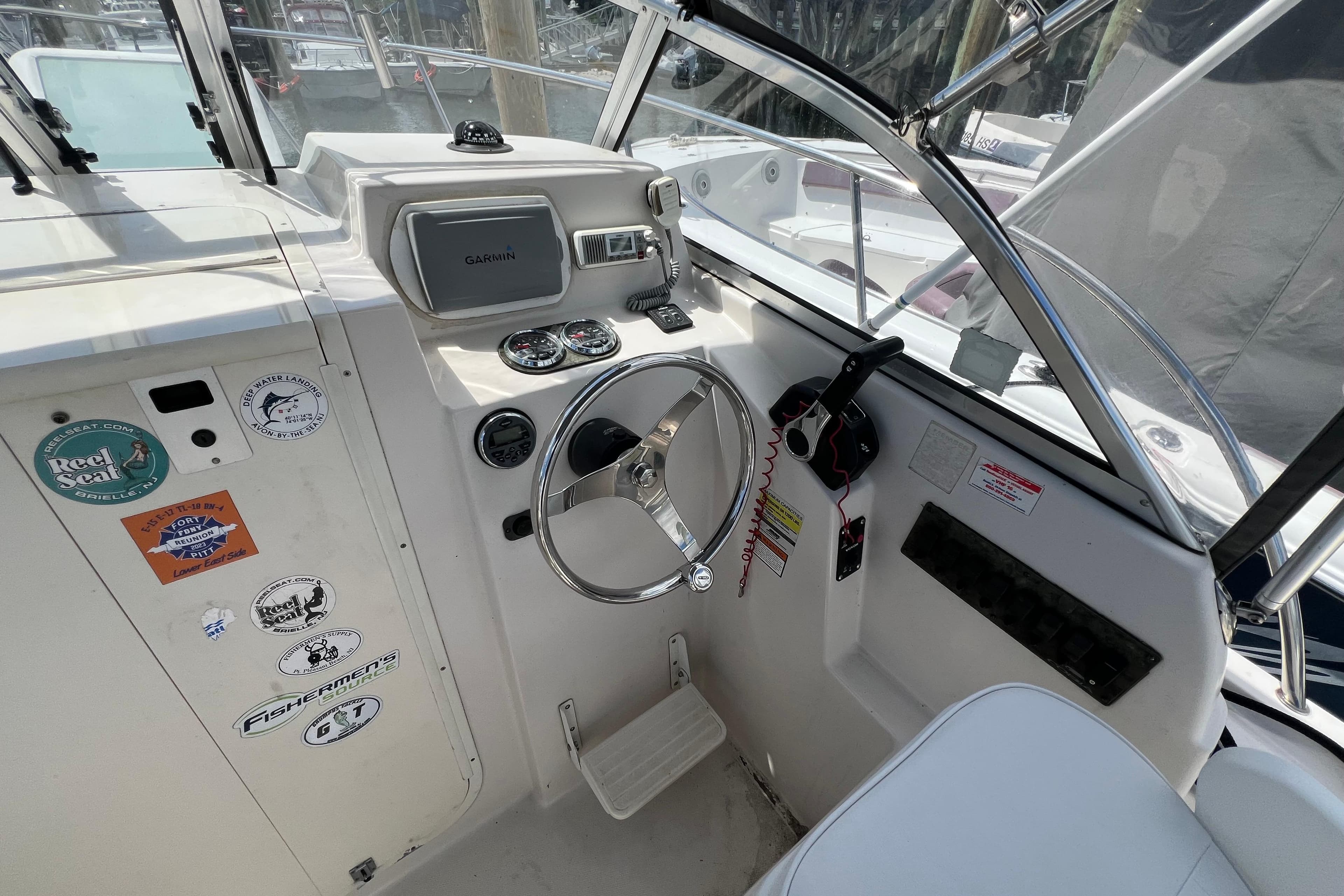 2008 Cobia 210 Walkaround boat cockpit with steering wheel, gauges, and Garmin navigation system.