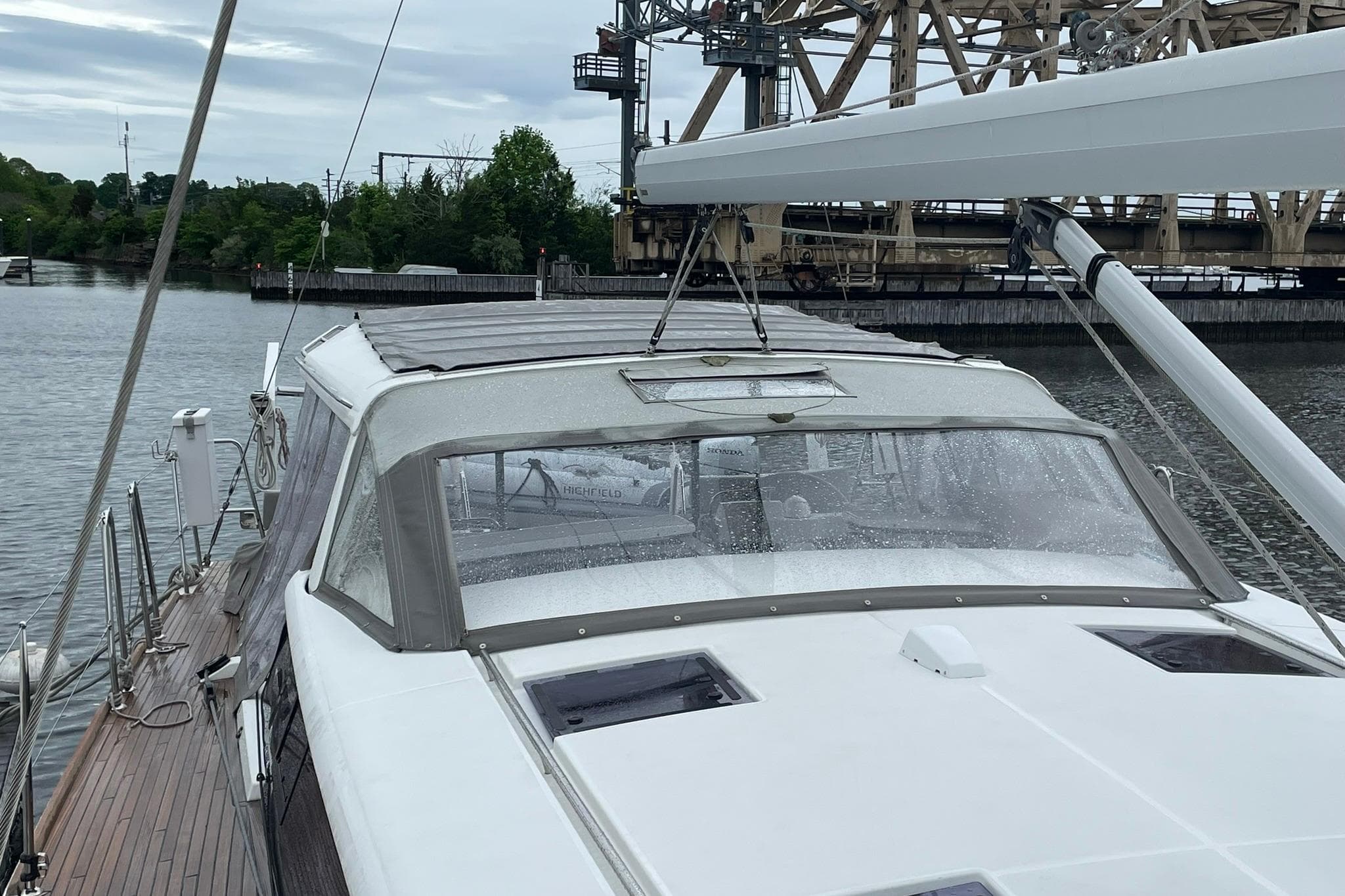 2017 Beneteau Sense 57 yacht docked near an industrial bridge on a cloudy day.