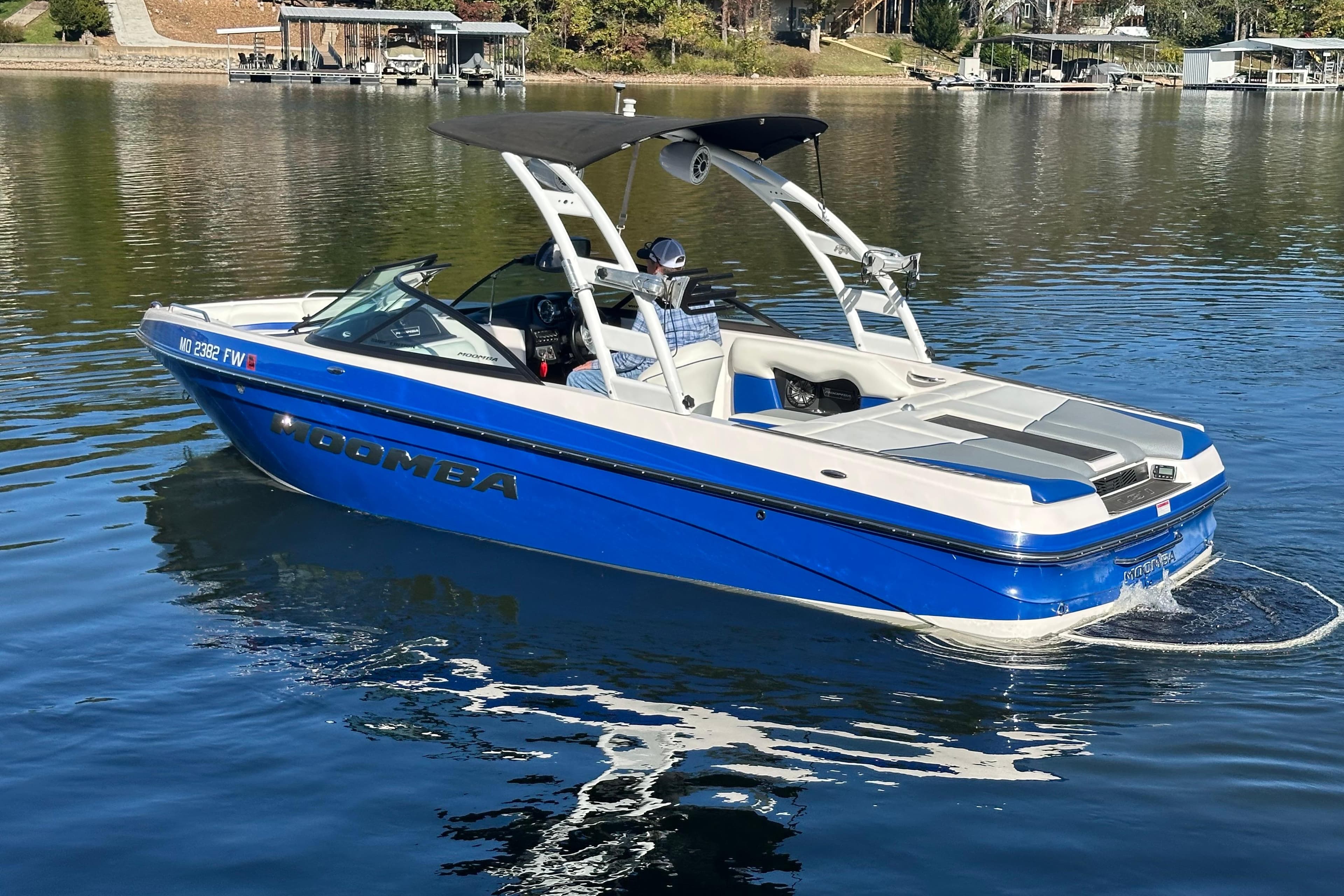 2015 Moomba Mobius LSV boat on a calm lake, featuring a blue and white design.