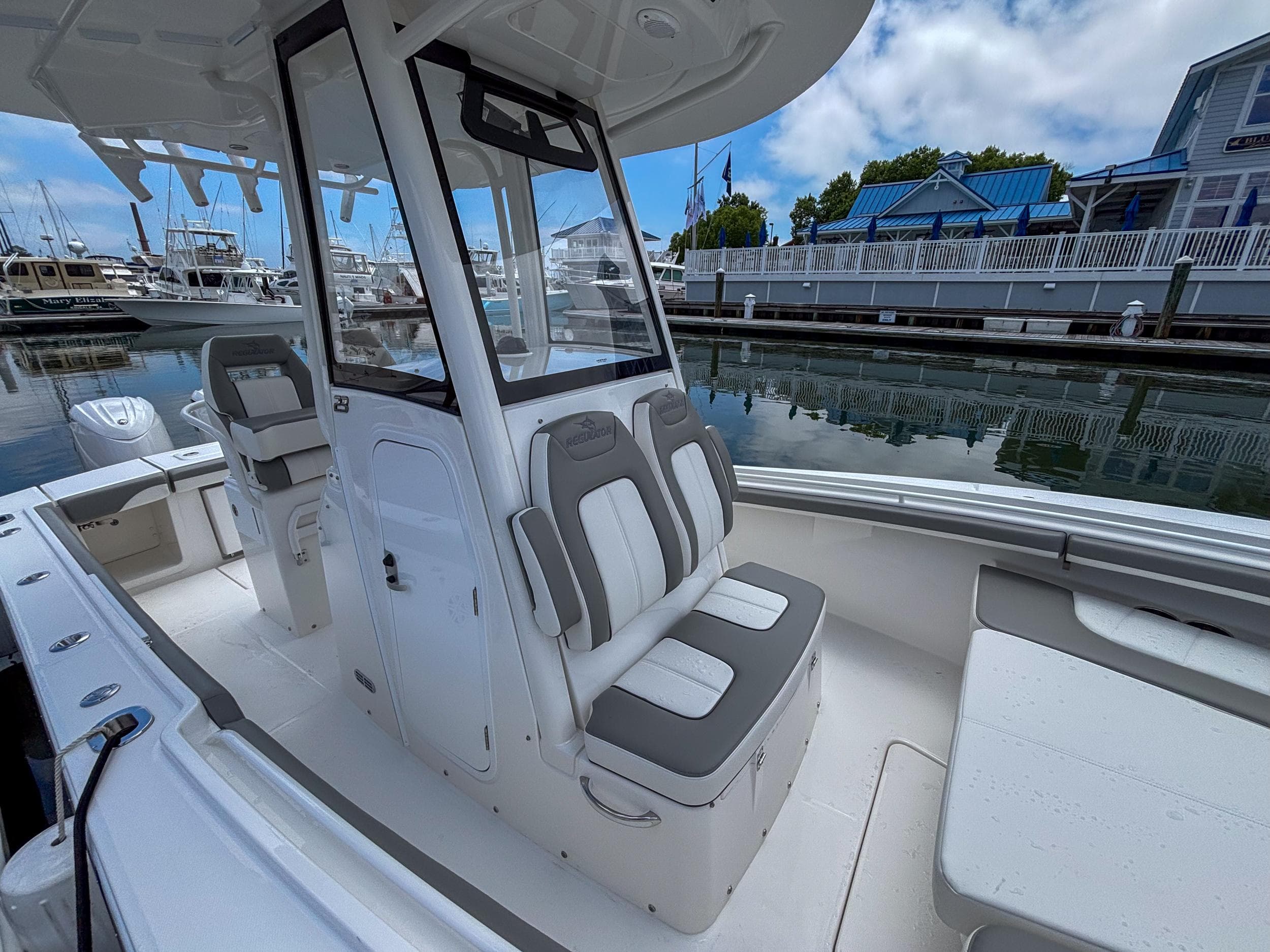 2025 Regulator 23 boat interior with seating, docked at a marina under a partly cloudy sky.
