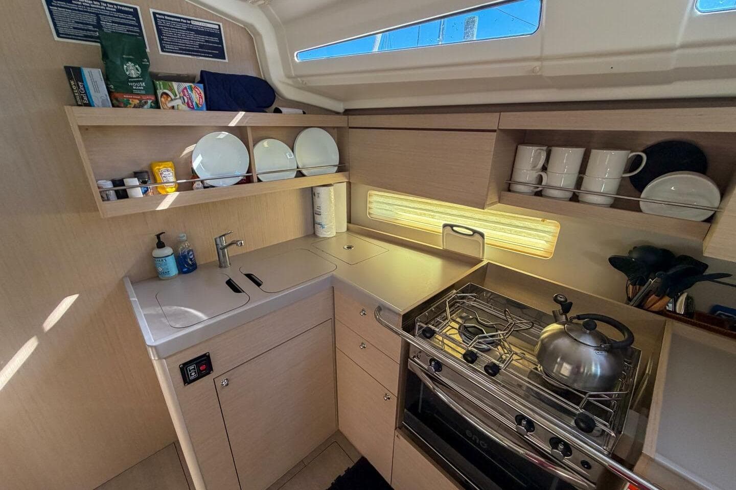 Modern kitchen in 2022 Beneteau Oceanis 40.1 yacht, featuring stove, sink, and storage.