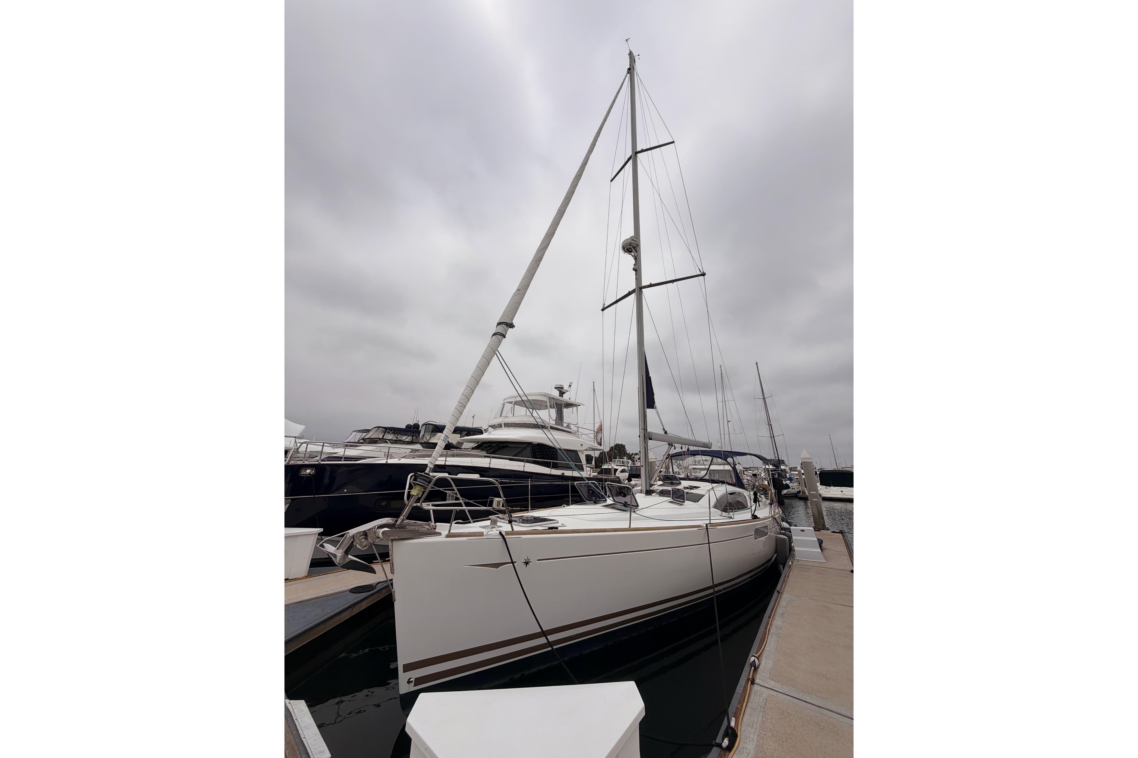 2014 Jeanneau Sun Odyssey 50 DS sailboat docked at marina under cloudy sky.
