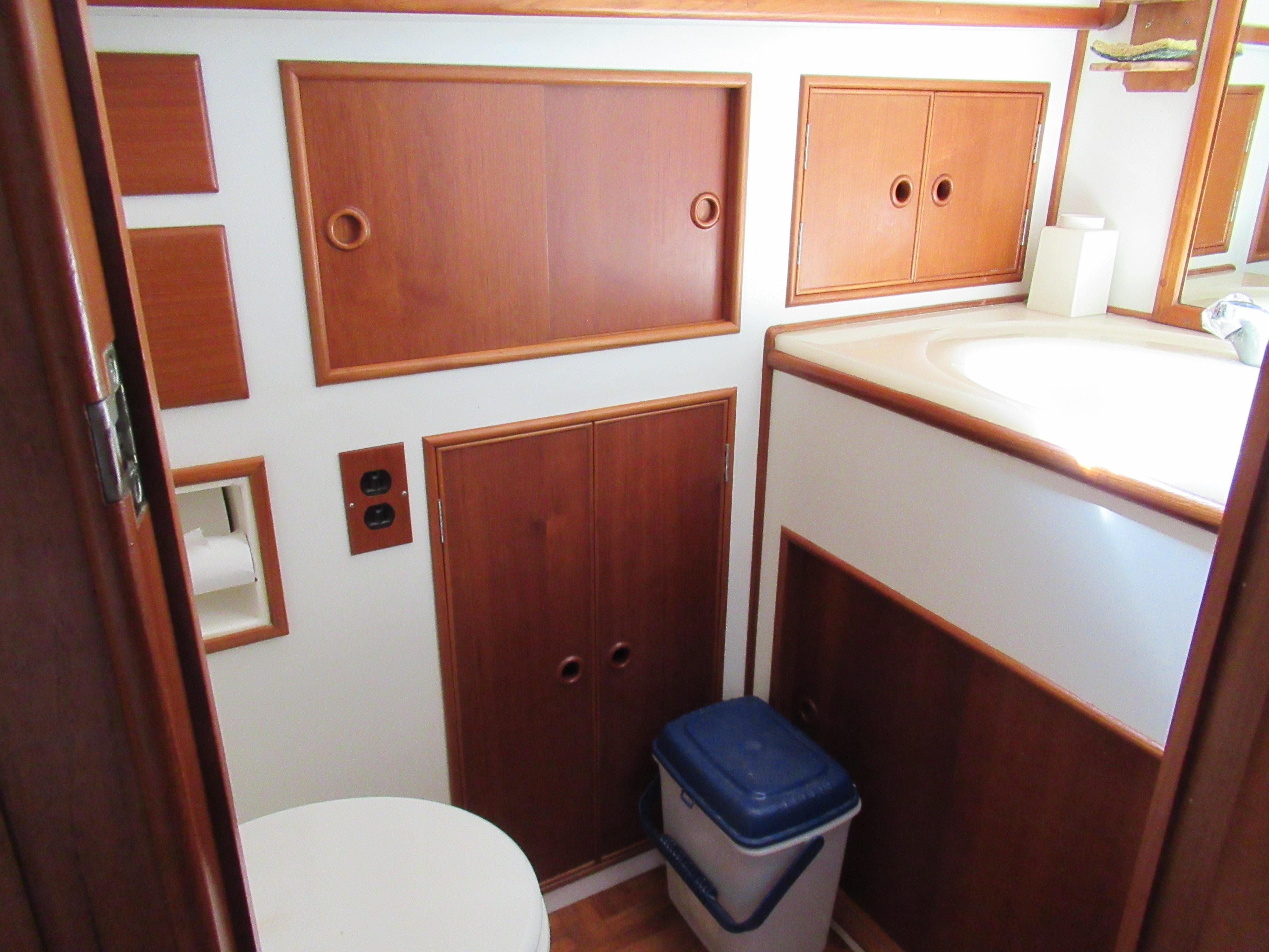 1990 Grand Banks Classic yacht bathroom with wooden cabinets and white fixtures.