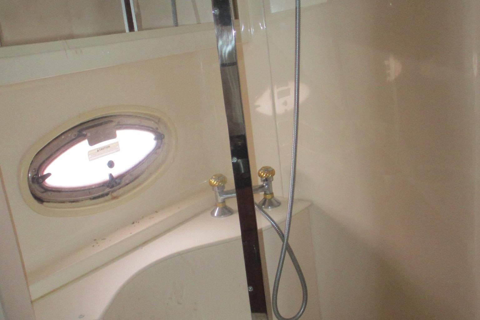 Shower area in 2006 Carver 466 Motor Yacht with oval window and chrome fixtures.