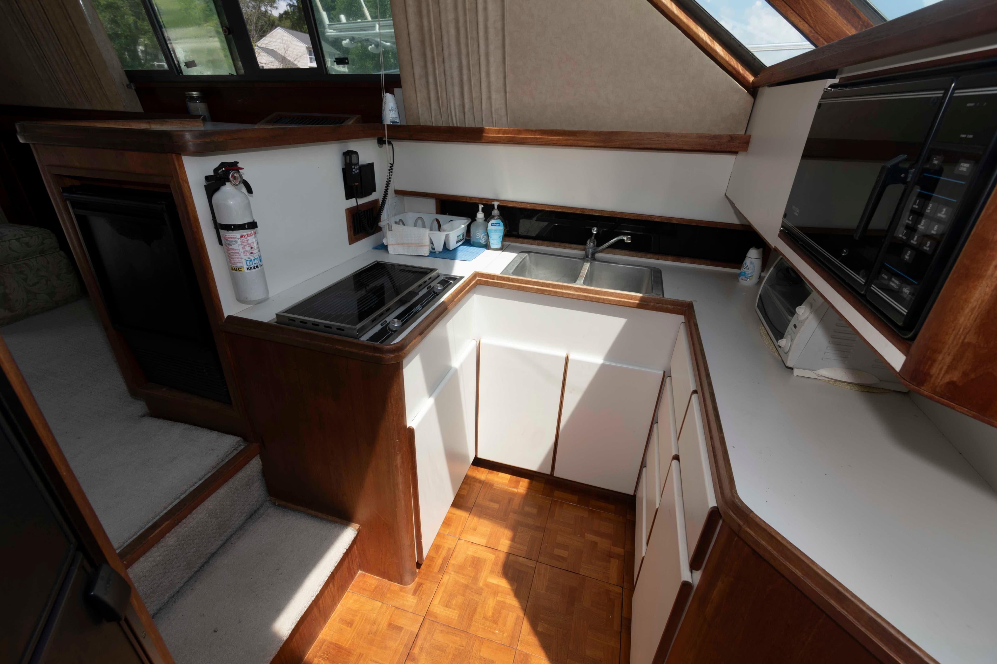 1989 Tiara Yachts 36 Convertible kitchen with stove, sink, and microwave.