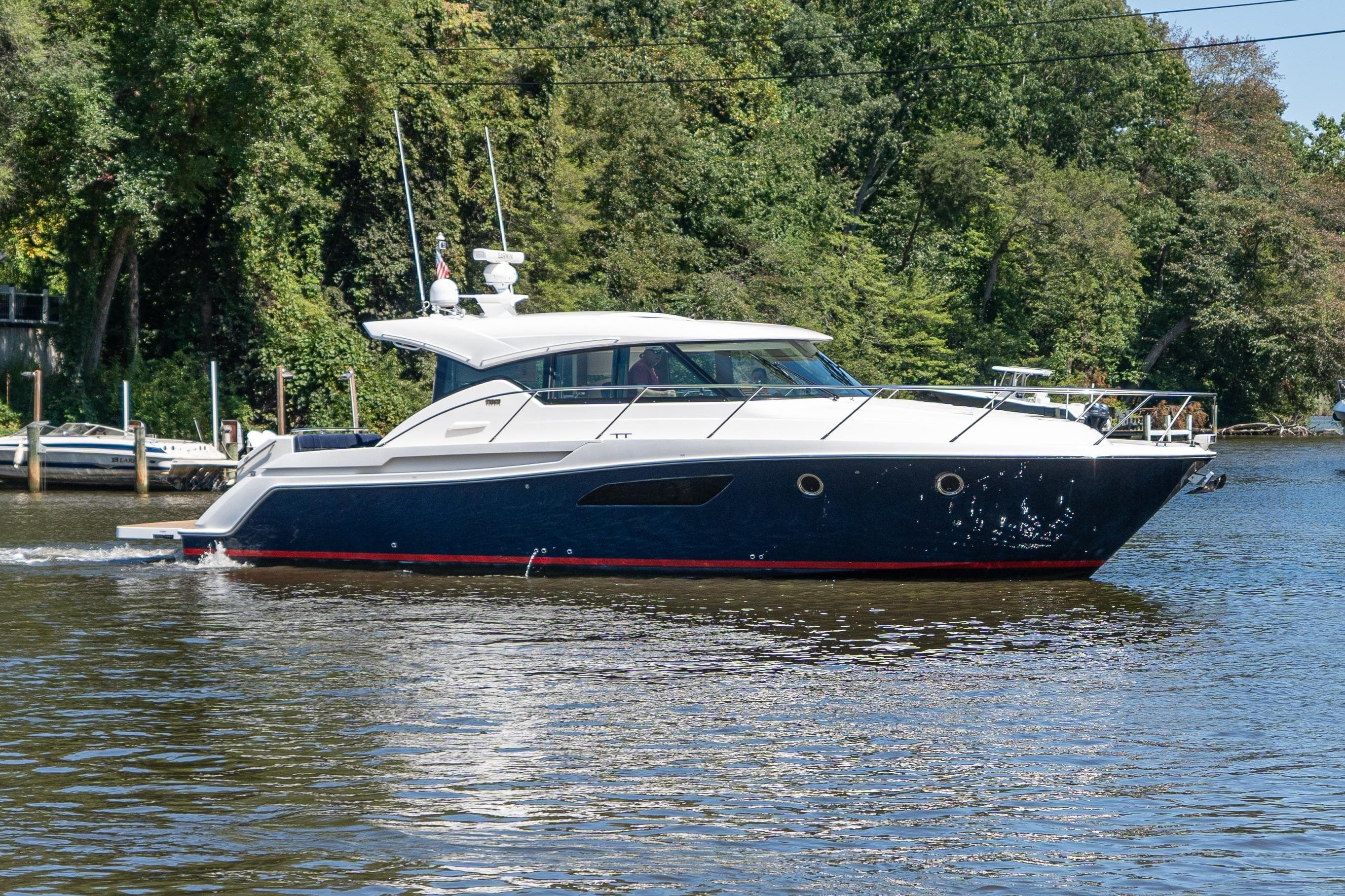 2015 Tiara Yachts C44 Coupe cruising on a scenic river with lush greenery.