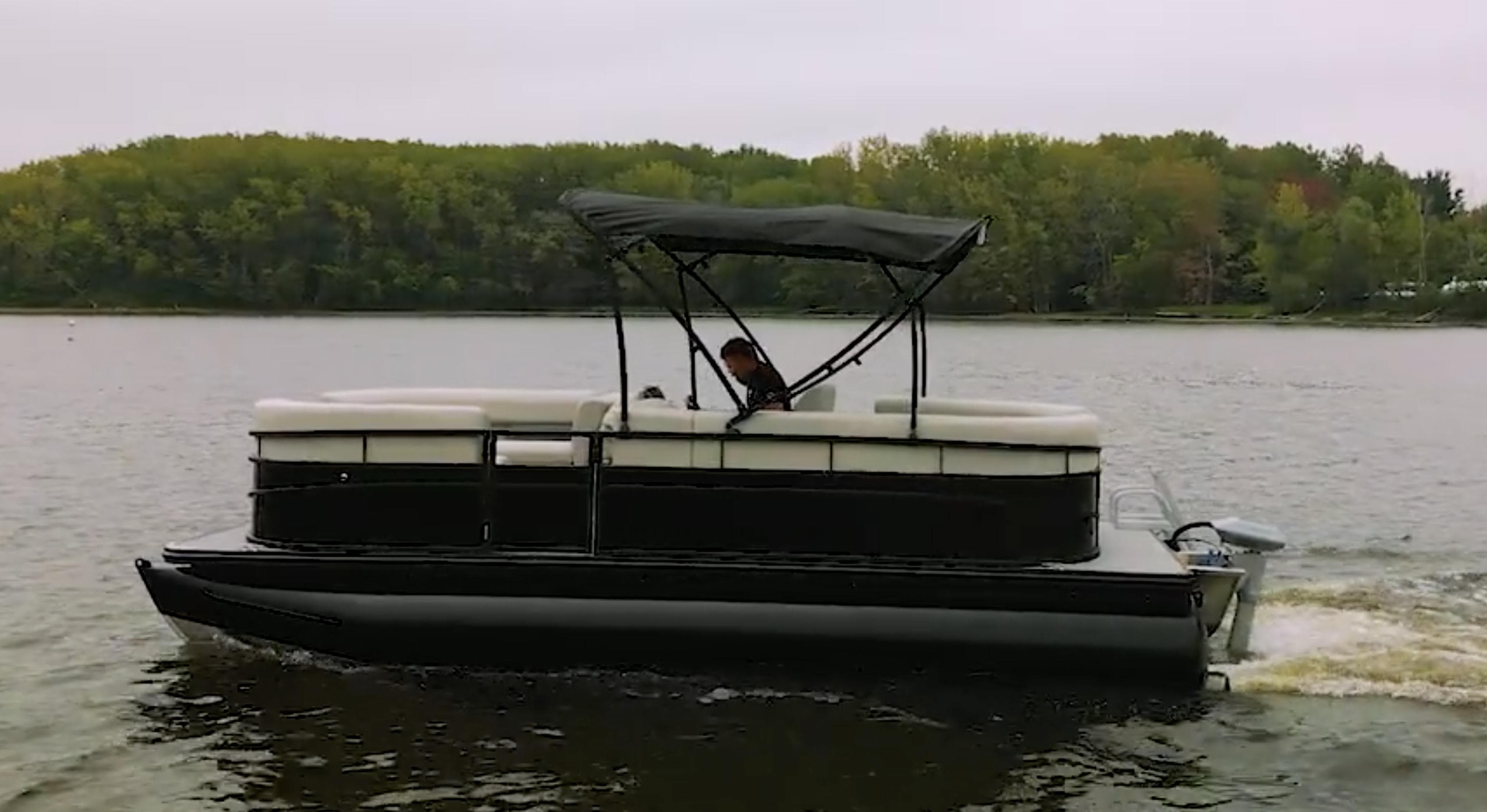 2024 Vision Marine Technologies WX Tritoon cruising on a lake with lush green trees in the background.