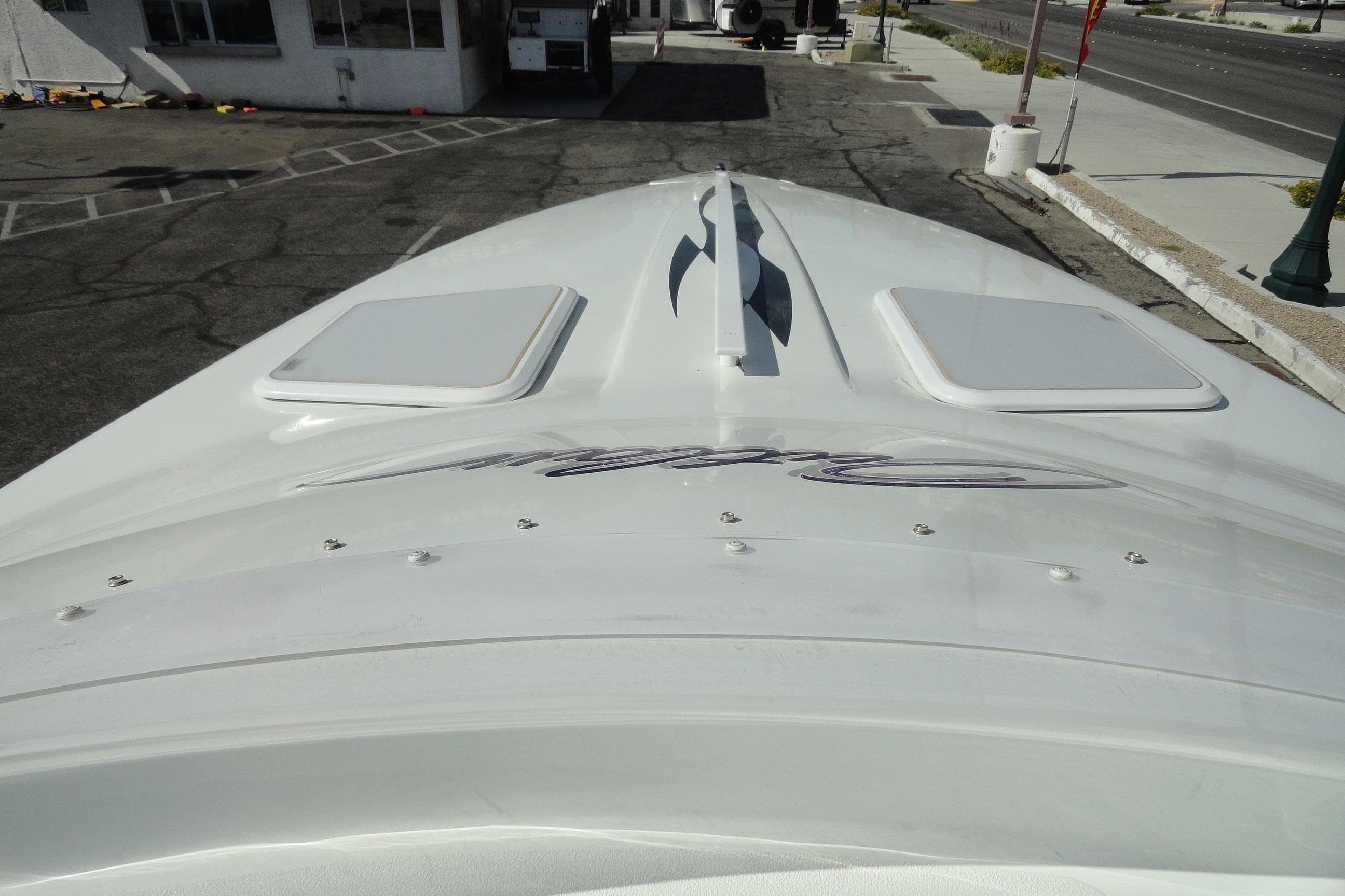 1998 Baja 29 Outlaw boat, top view, parked on asphalt near a building.