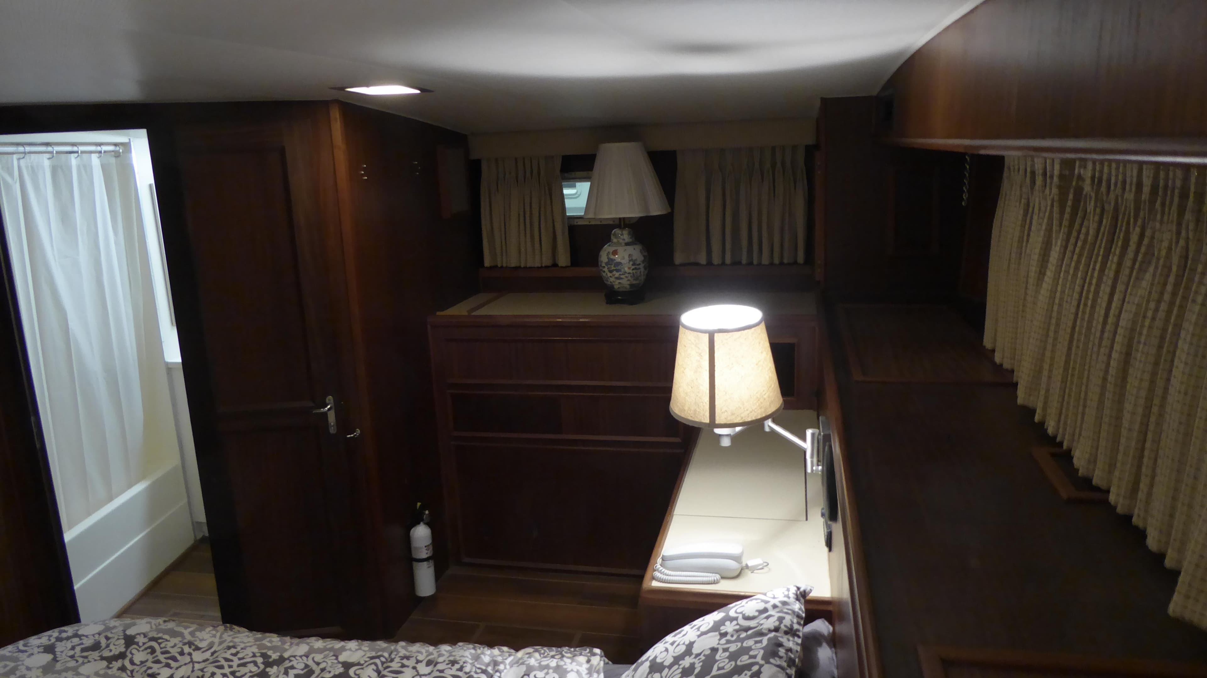 1985 Hatteras 56 Motor Yacht interior with wood paneling, bed, and lamps.