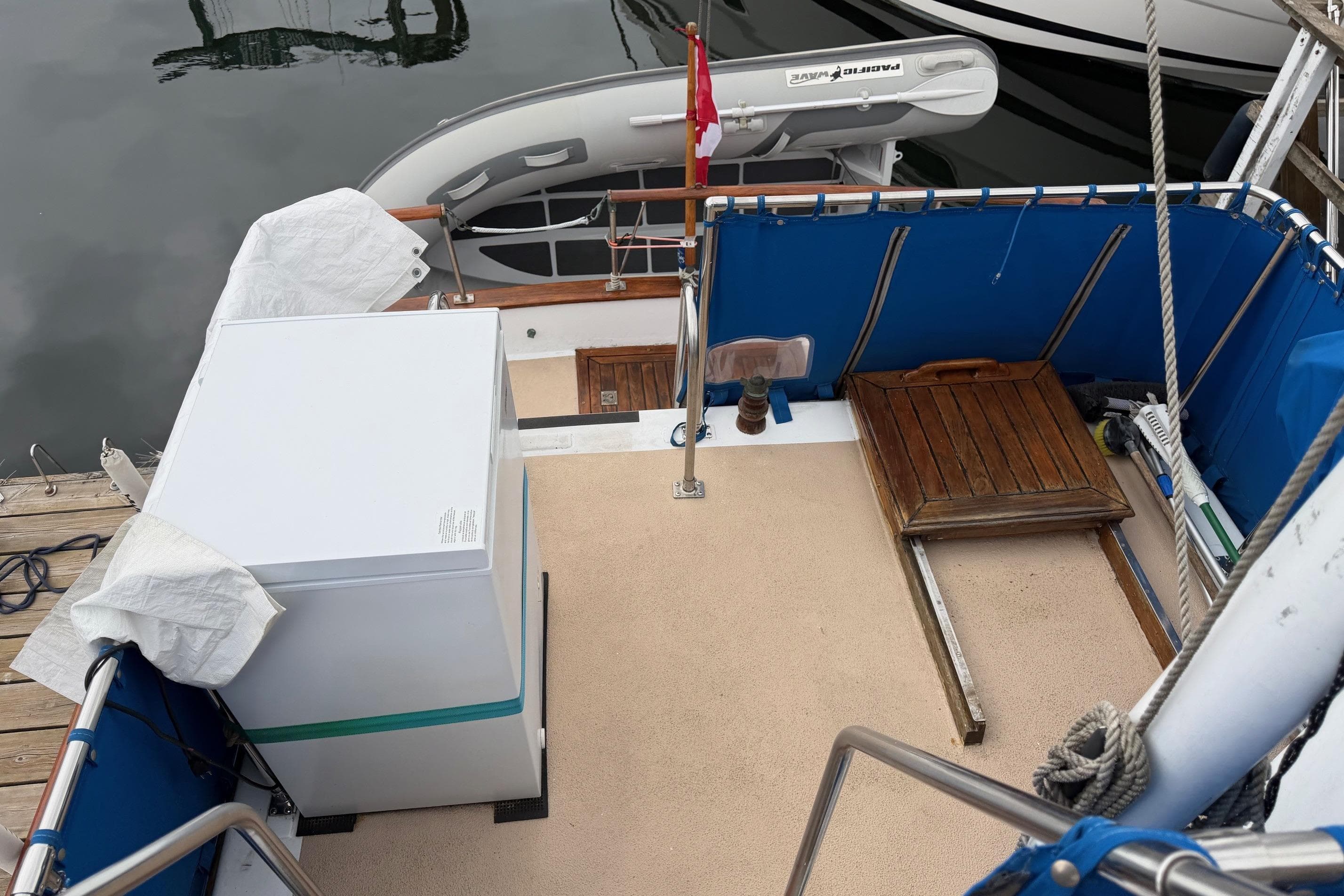 1978 CHB 34 Tri Cabin boat deck with blue railing and docked dinghy.