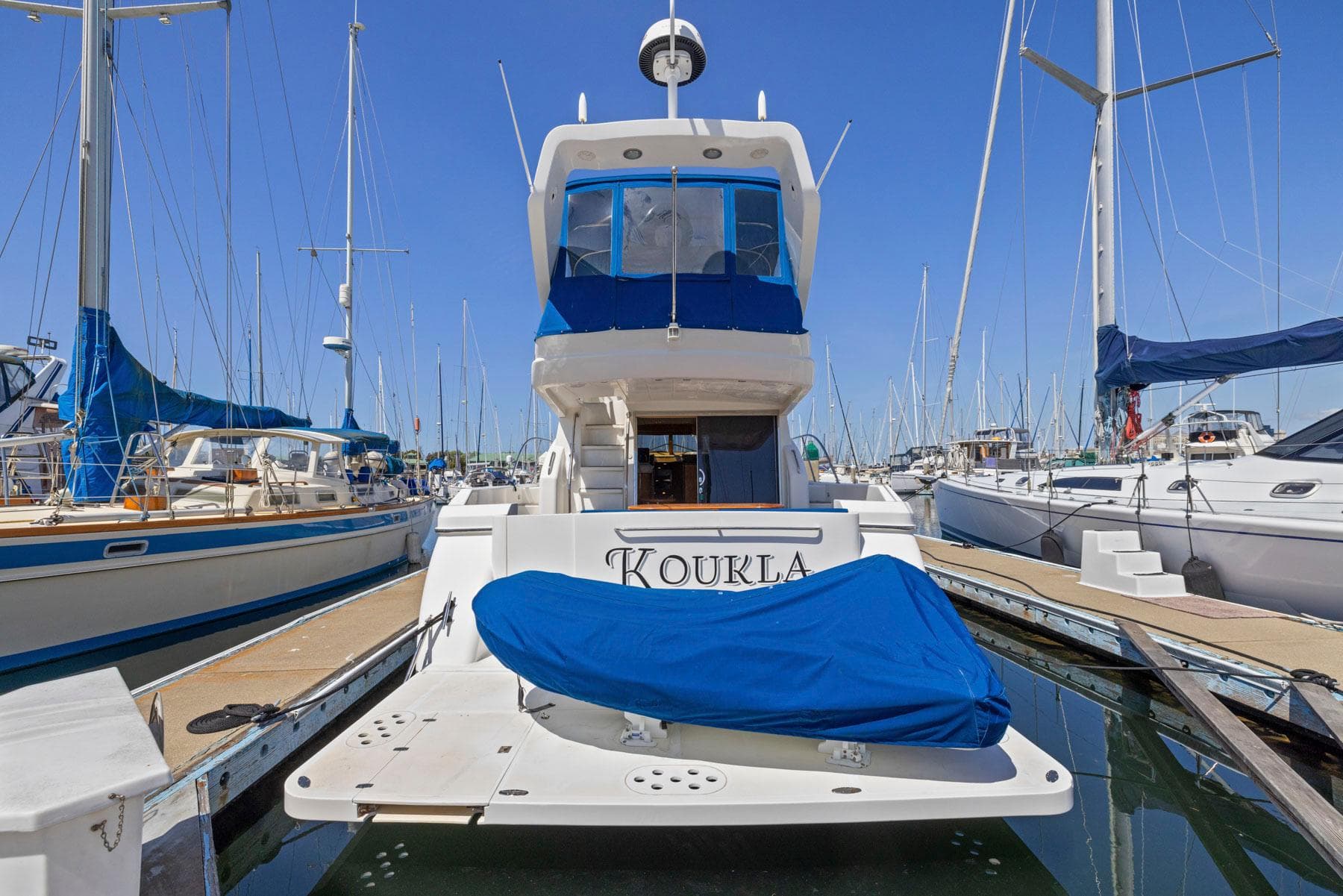 2008 Dyna 51 yacht docked at marina, covered in blue tarp, surrounded by sailboats.
