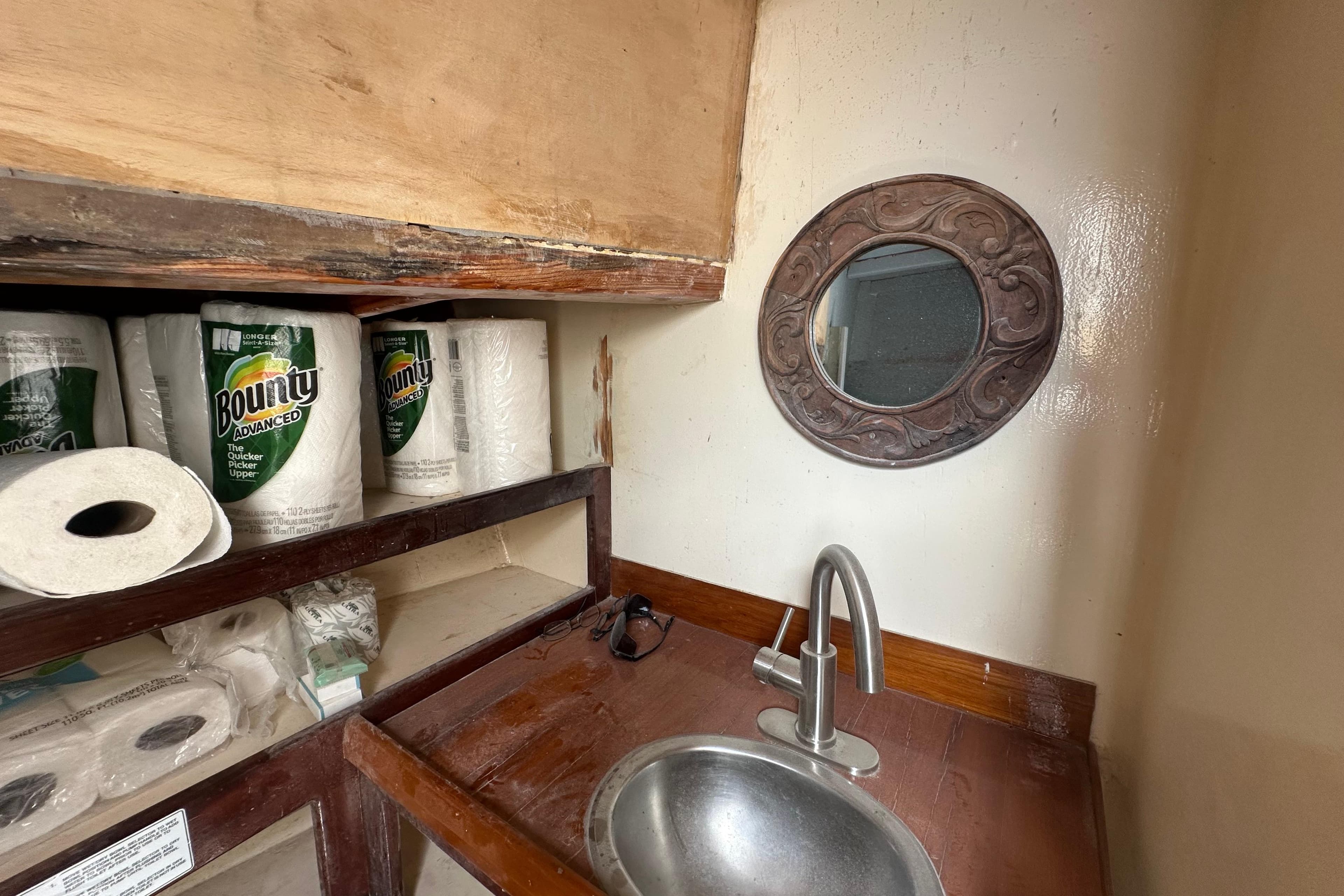 Small boat bathroom with sink, mirror, and paper towels on Schooner Leopard, 1994.