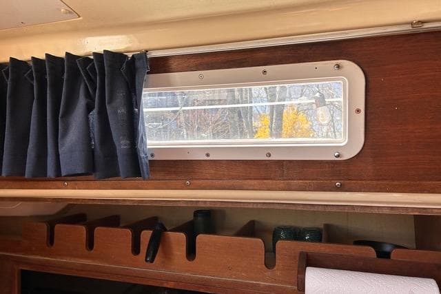 Interior of a 1984 Pearson 34 sailboat with a window and blue curtain.