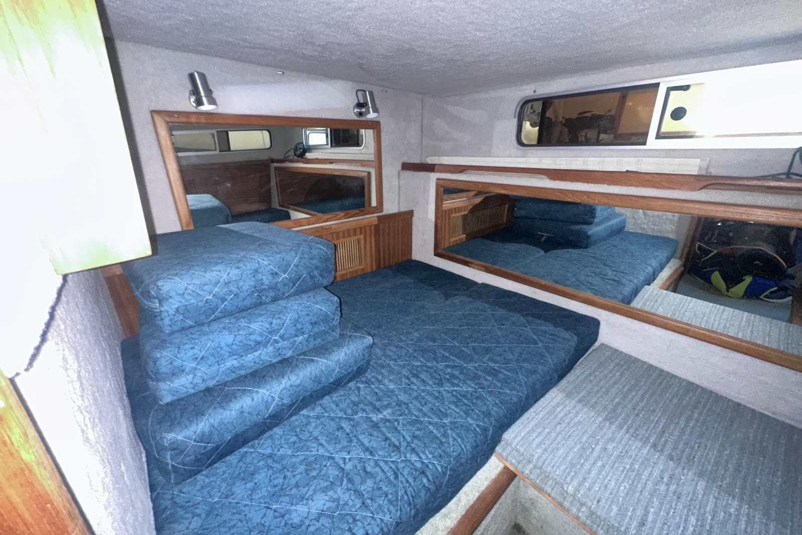 Interior cabin of 1987 Sea Ray 300 Sundancer with blue bedding and wood accents.