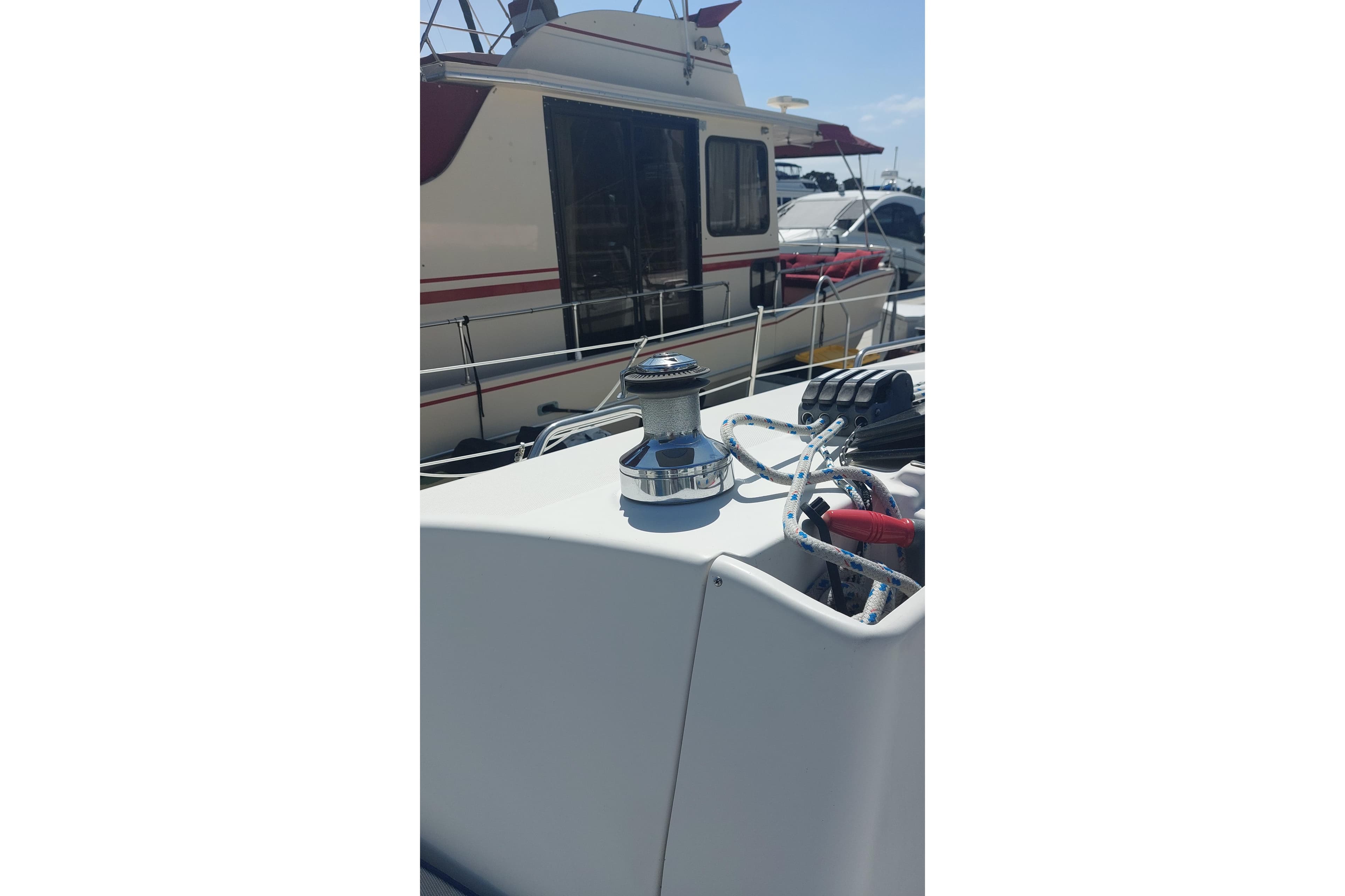 2005 Hunter 38 sailboat deck with winch and ropes in marina setting.