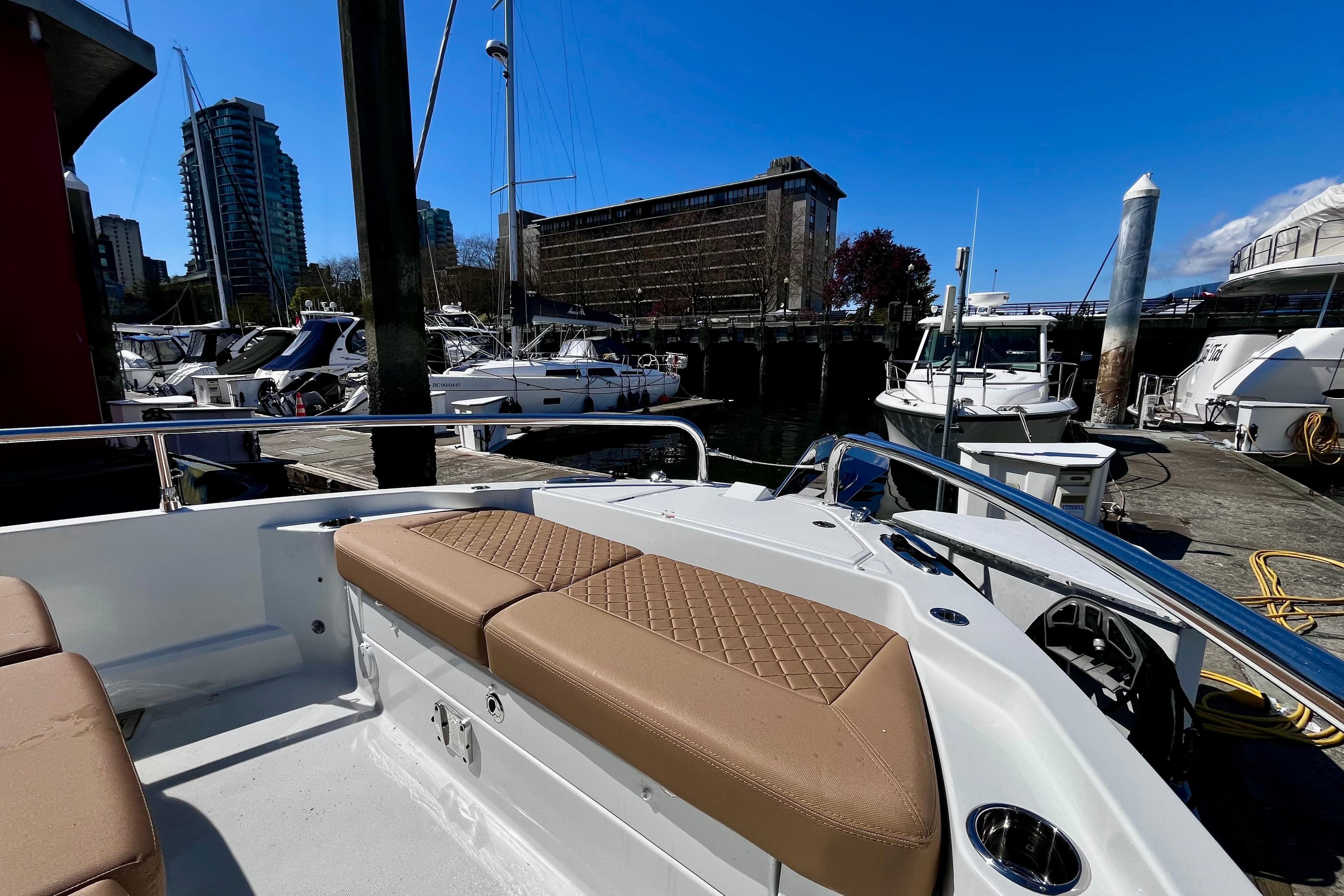 2025 Wellcraft 38 Explorer docked at marina, featuring tan seating and urban skyline backdrop.