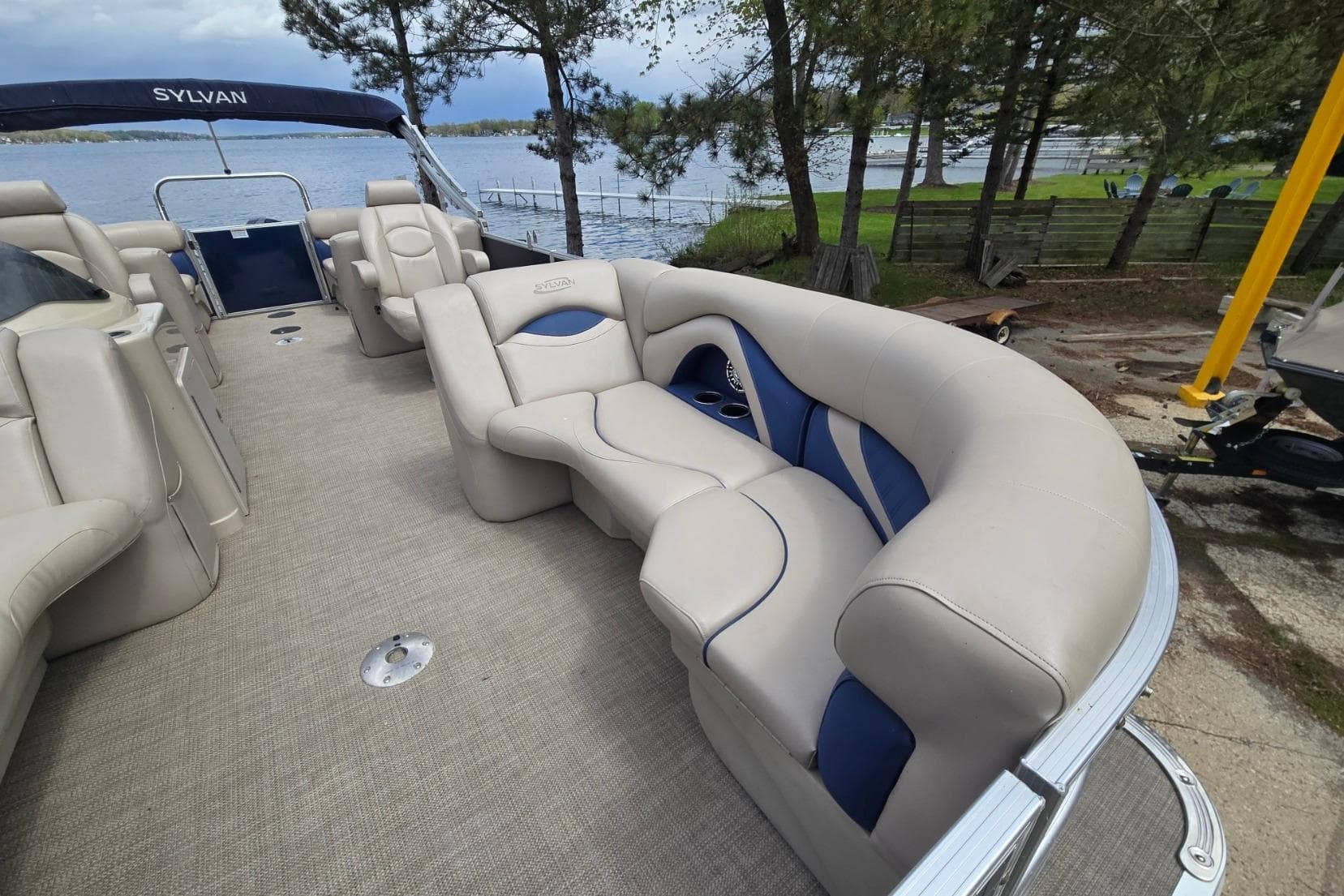 2016 Sylvan Mirage Cruise 8522 LZ pontoon boat with plush seating by a lakeside.