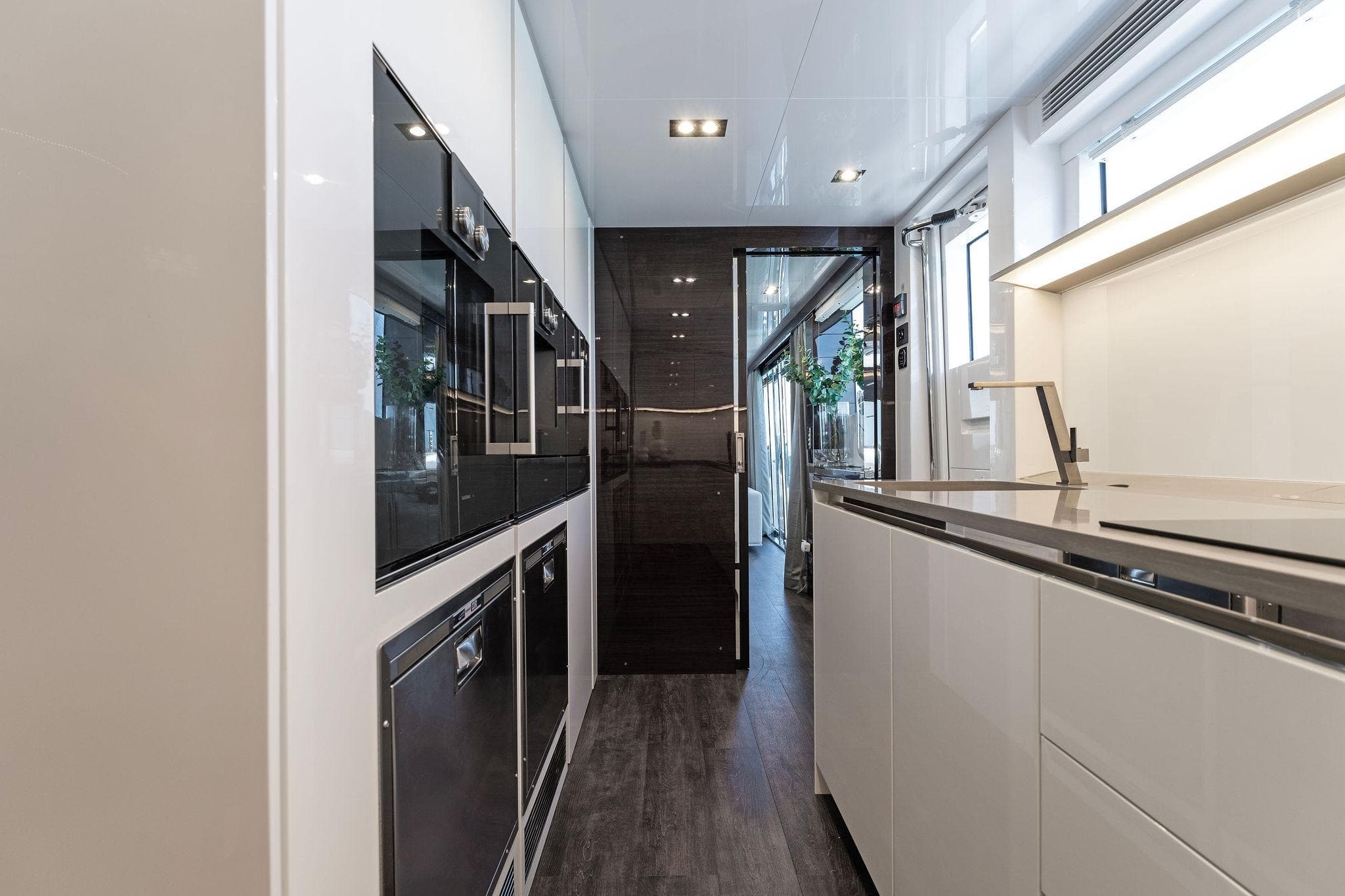 Modern kitchen interior on a 2023 Pearl 95 yacht, featuring sleek cabinetry and stainless steel appliances.