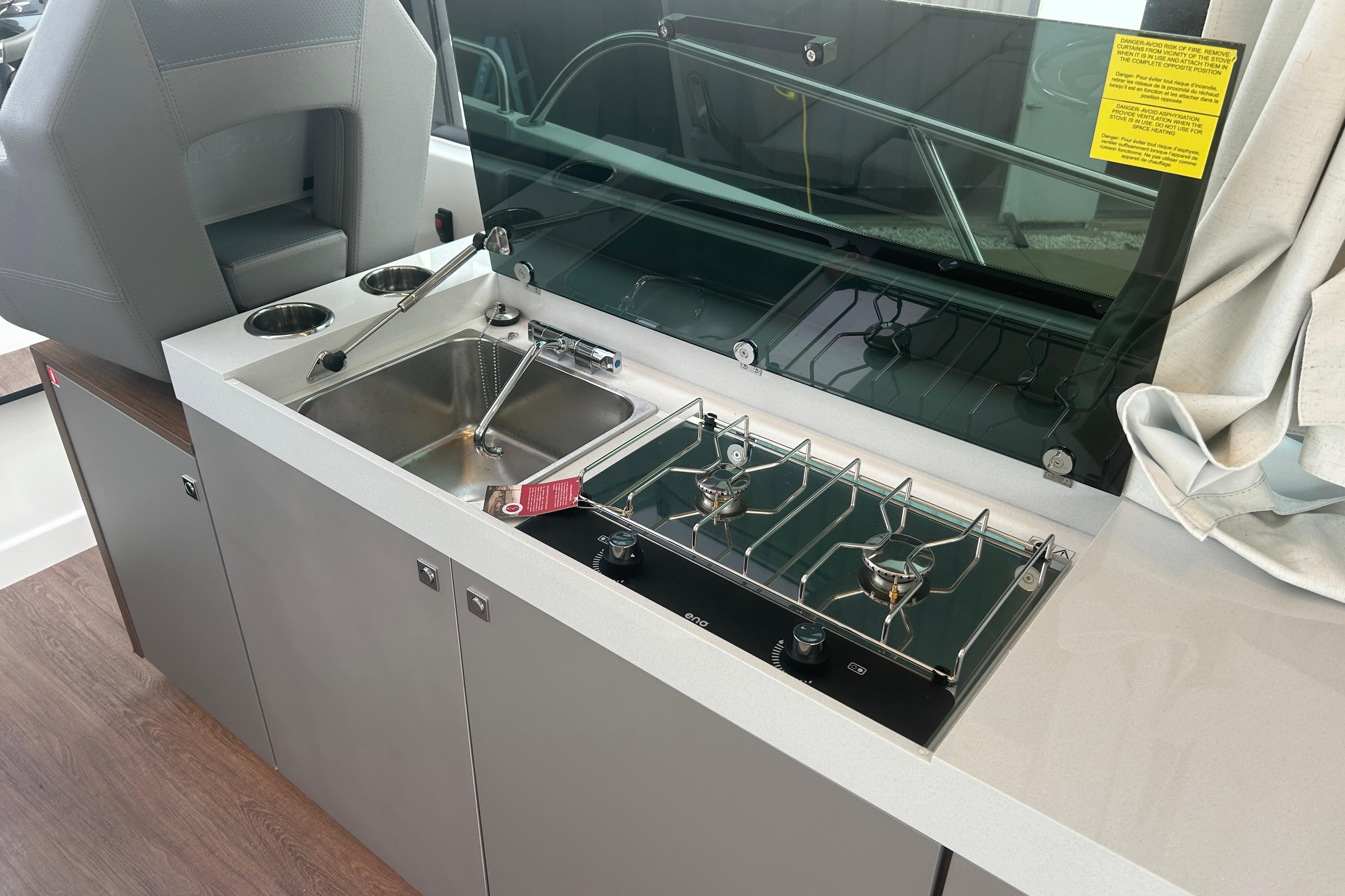 2025 Beneteau Antares 11 Coupe kitchen with sink and dual-burner stove.