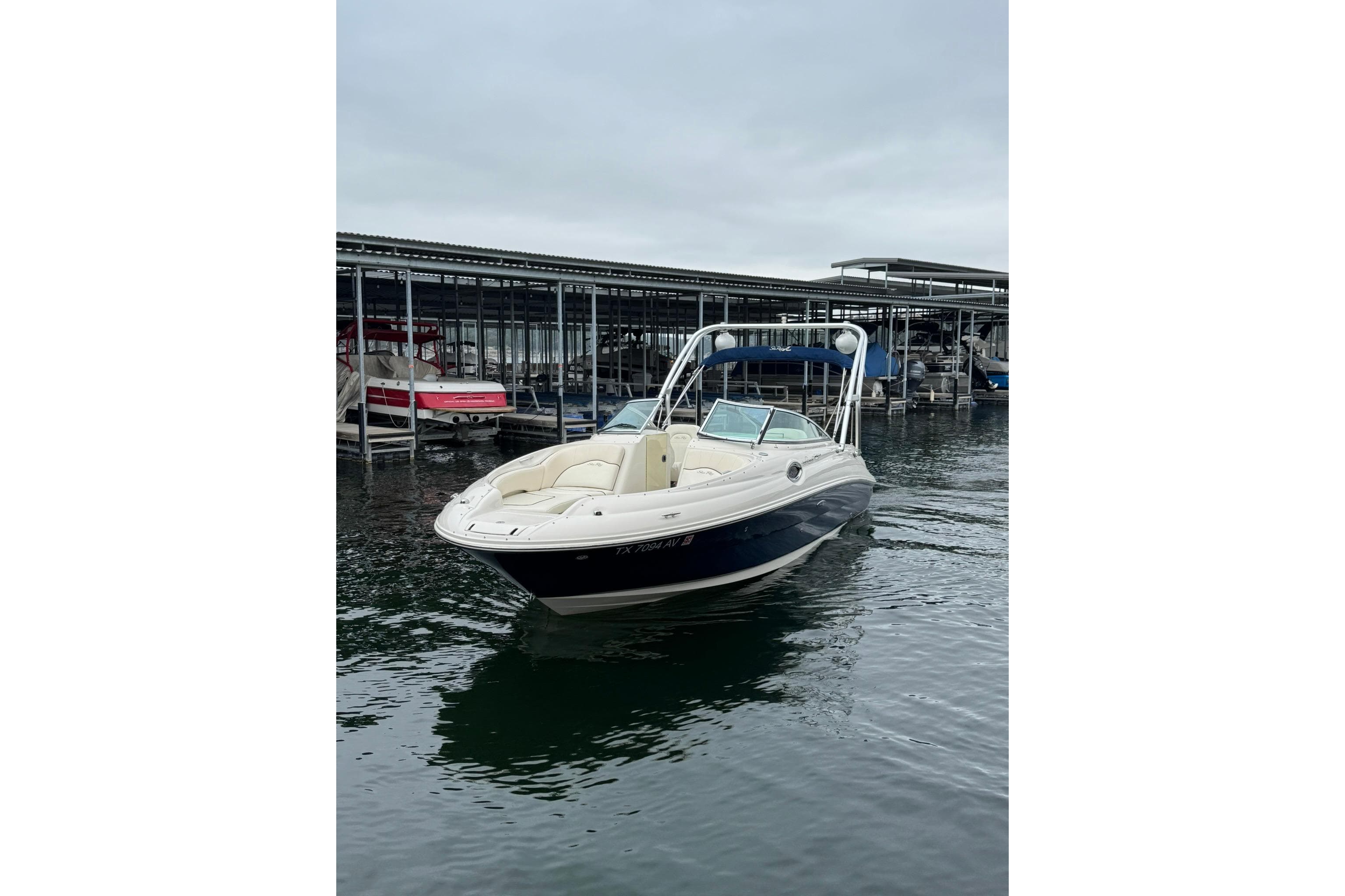2008 Sea Ray 240 Sundeck boat docked on calm water under cloudy skies.