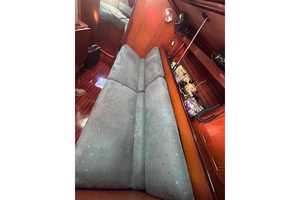 Interior of 1987 Beneteau First 375 sailboat with cushioned seating and wooden paneling.