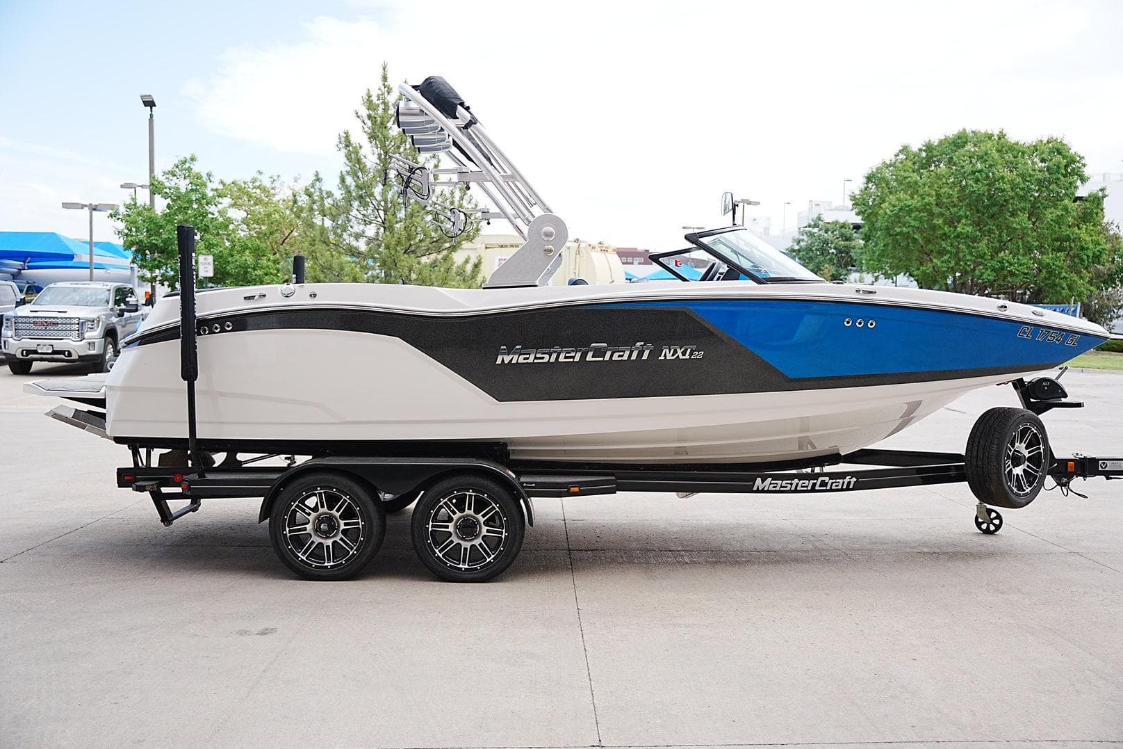 2019 MasterCraft NXT22 boat on trailer, blue and white design, parked outdoors.