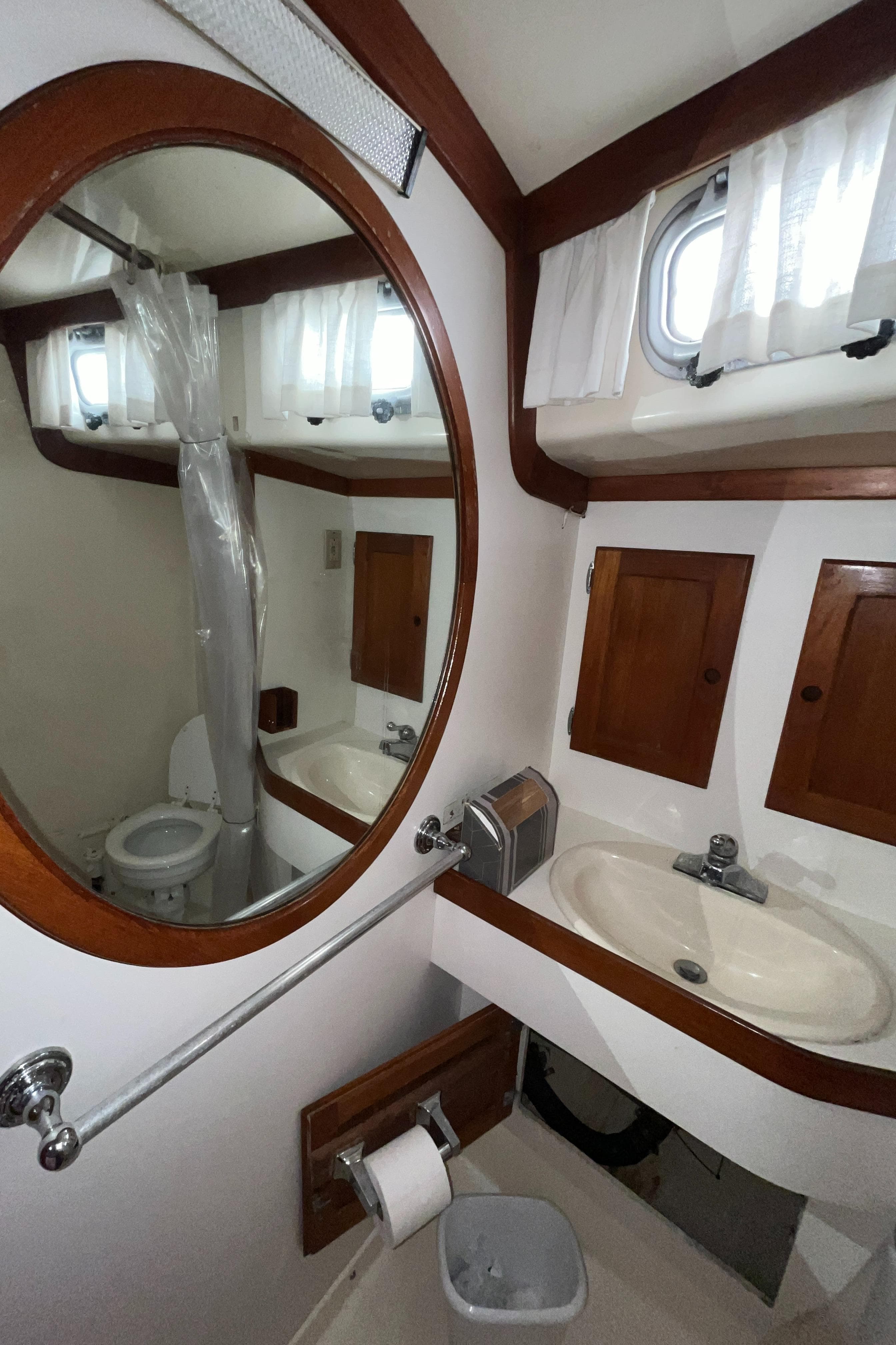 1986 Bristol 38.8 yacht bathroom with sink, mirror, and wooden cabinets.
