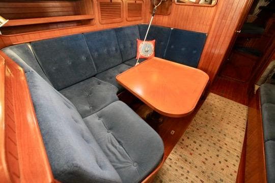 Cozy 1981 Ta-Shing Panda 40 yacht interior with blue cushioned seating and wooden table.