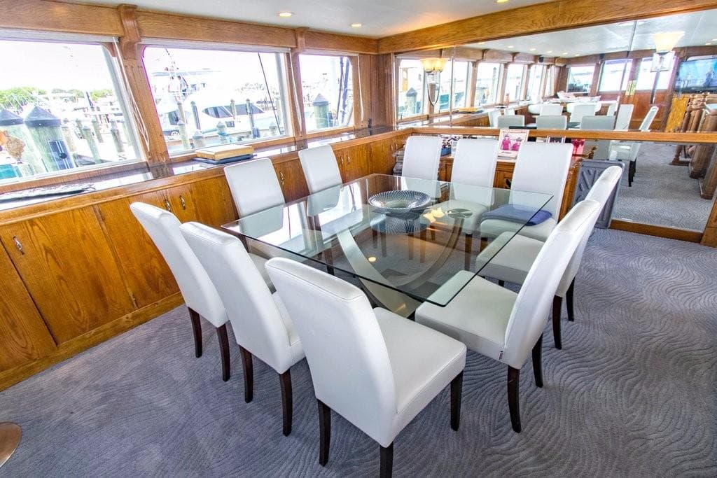 Luxurious dining area on 1983 Benetti Custom Lloyds M.Y. yacht with glass table and white chairs.