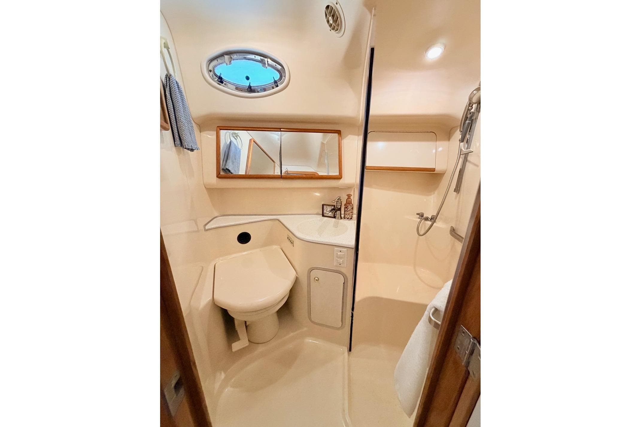 1997 Sea Ray 420 Aft Cabin bathroom with shower, sink, and porthole window.