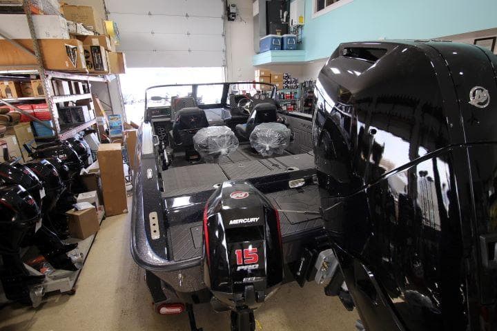 2025 Vexus DVX22S boat with Mercury engine in showroom, surrounded by equipment and accessories.