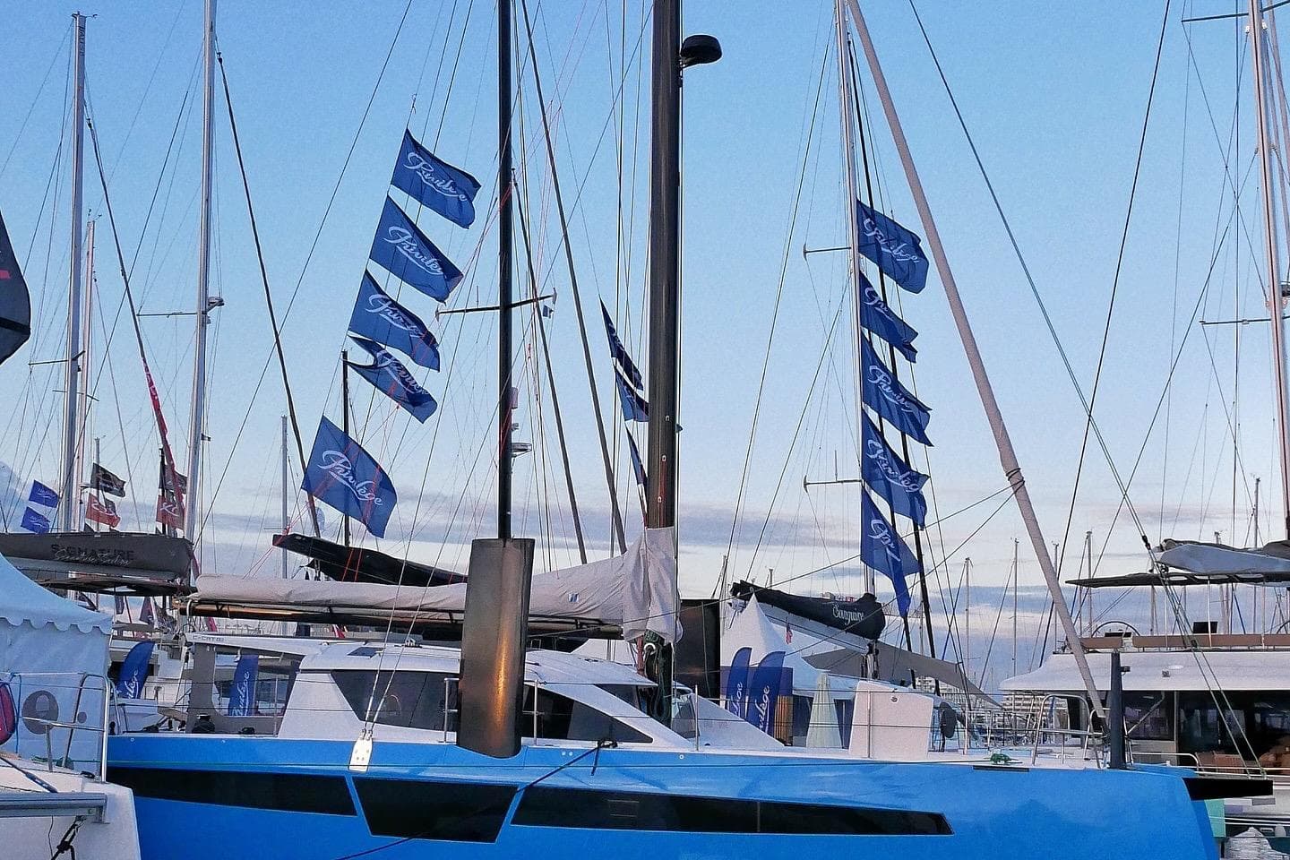 2025 C-Catamarans 48 yacht with blue hull and multiple flags at a marina.