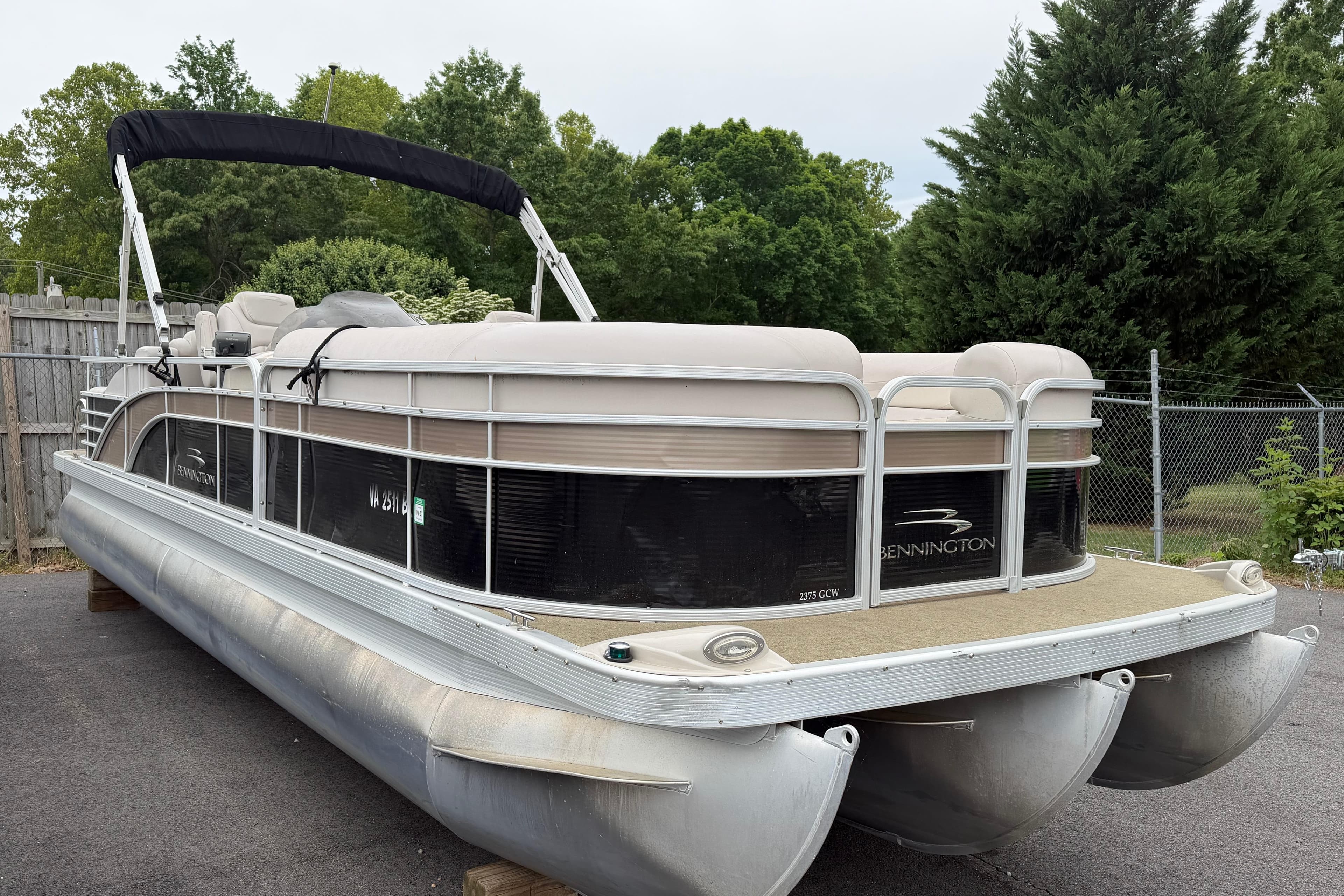 2013 Bennington 2375 GCW pontoon boat parked on pavement with lush greenery background.