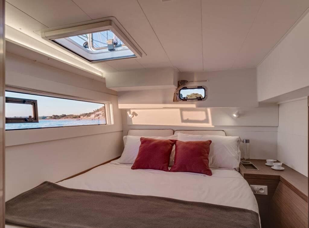 Luxurious 2024 Lagoon 40 yacht cabin with scenic ocean view and elegant bedding.