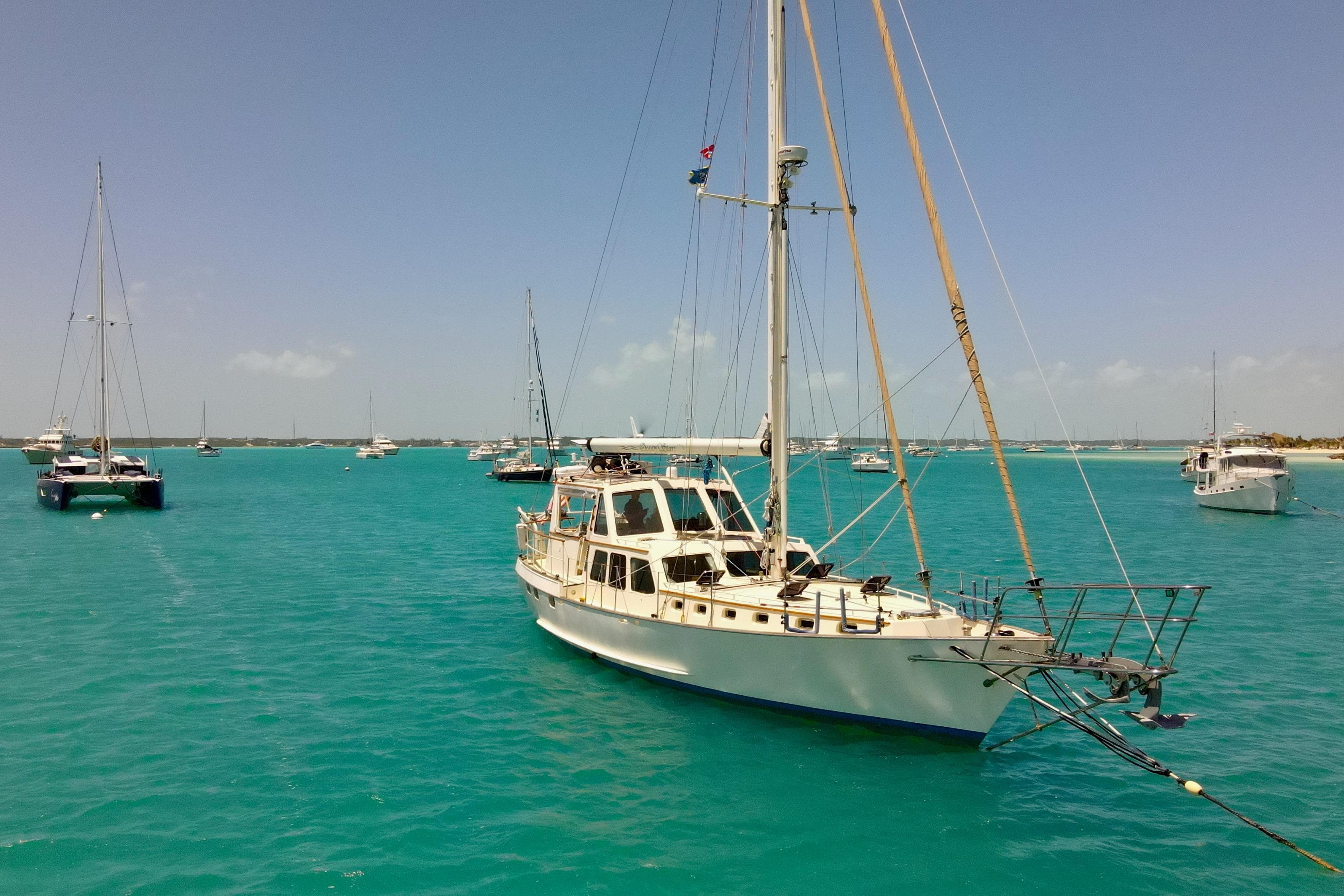Sailboats anchored in turquoise waters, featuring a 1995 Benford Custom Pilothouse Cutter.