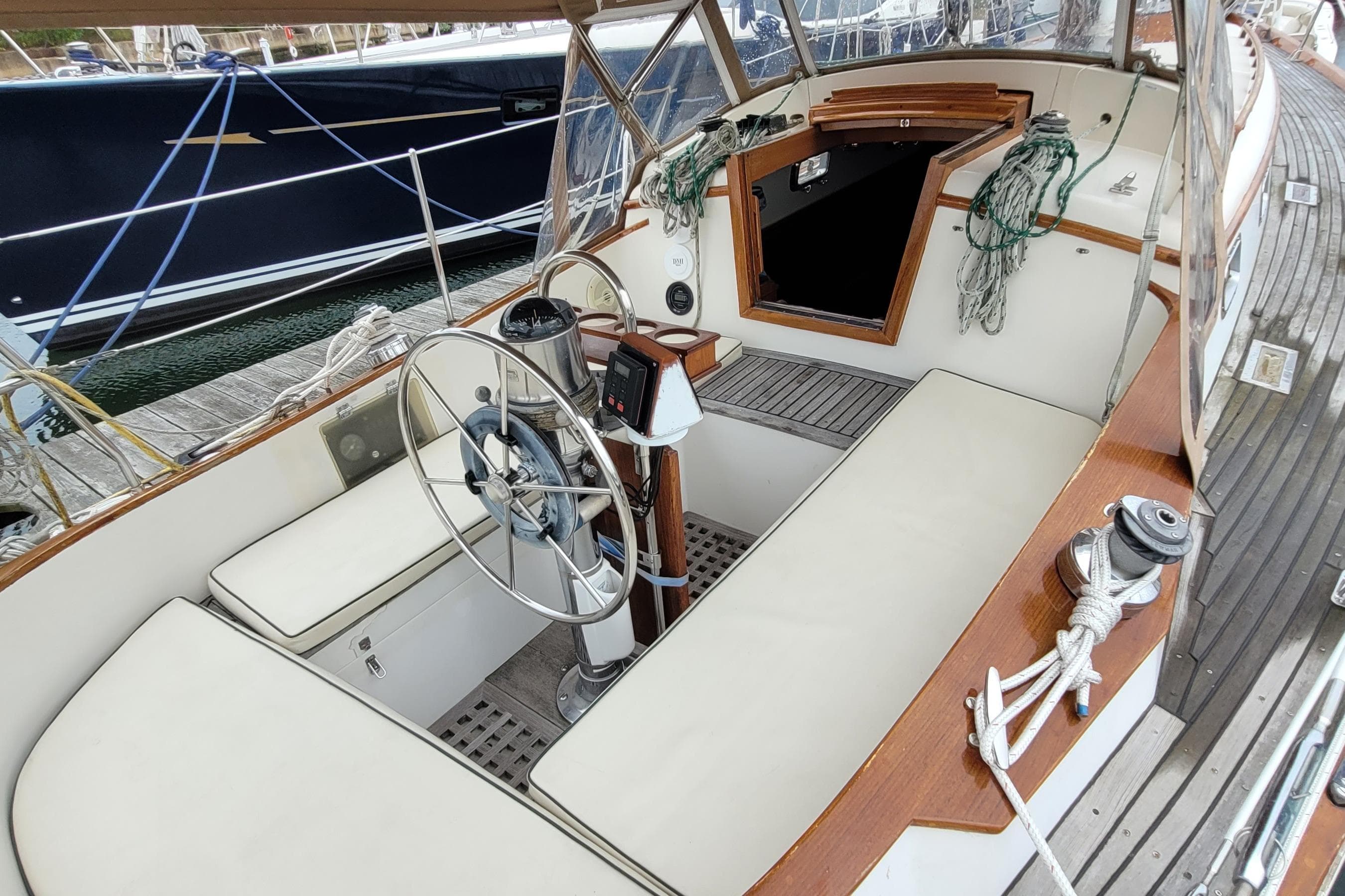 1985 Mason 33 Sloop cockpit with steering wheel, seating, and nautical ropes.