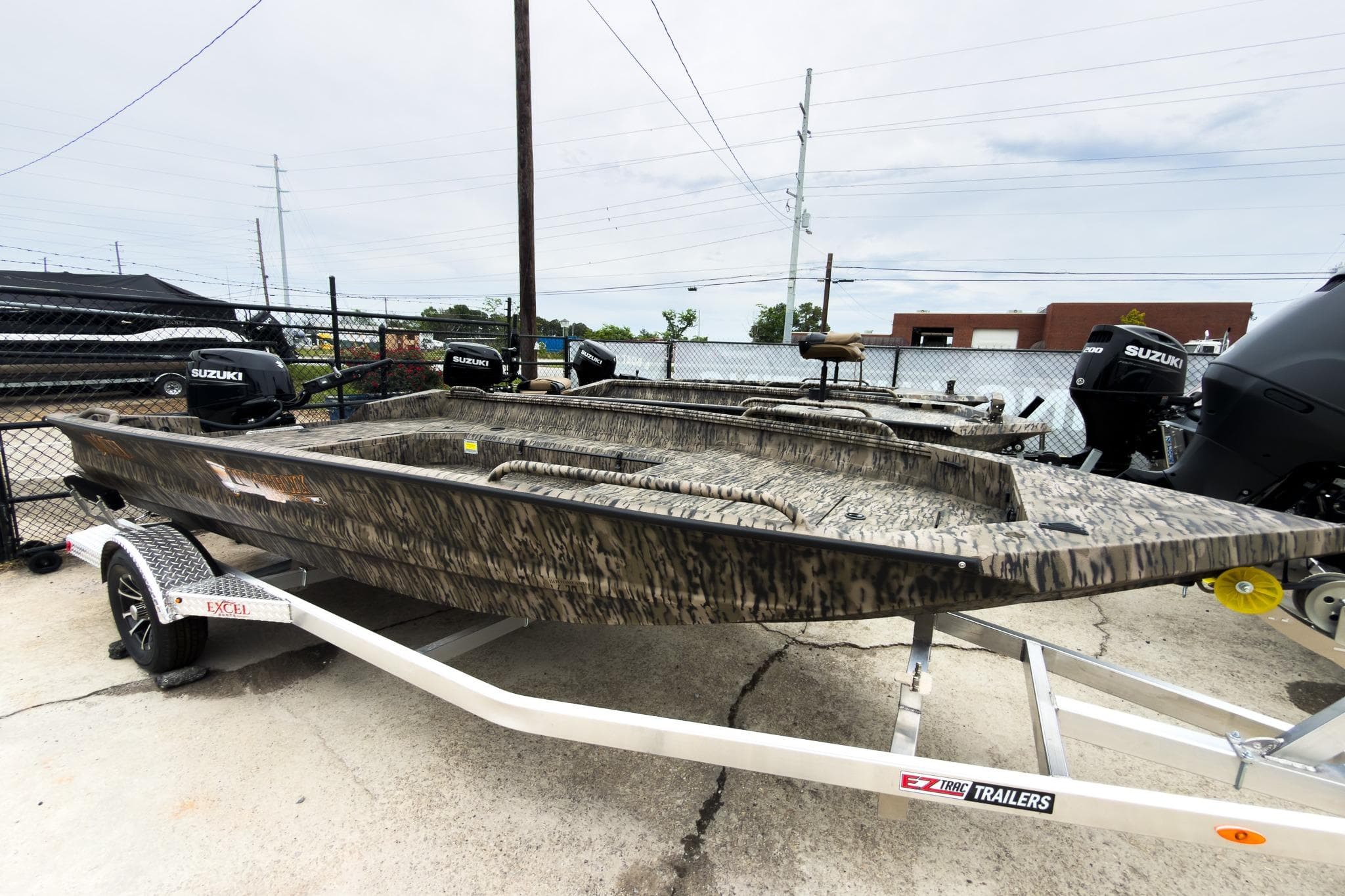 2026 Excel 183 Tomahawk boat on trailer, featuring camouflage design and Suzuki outboard motors.
