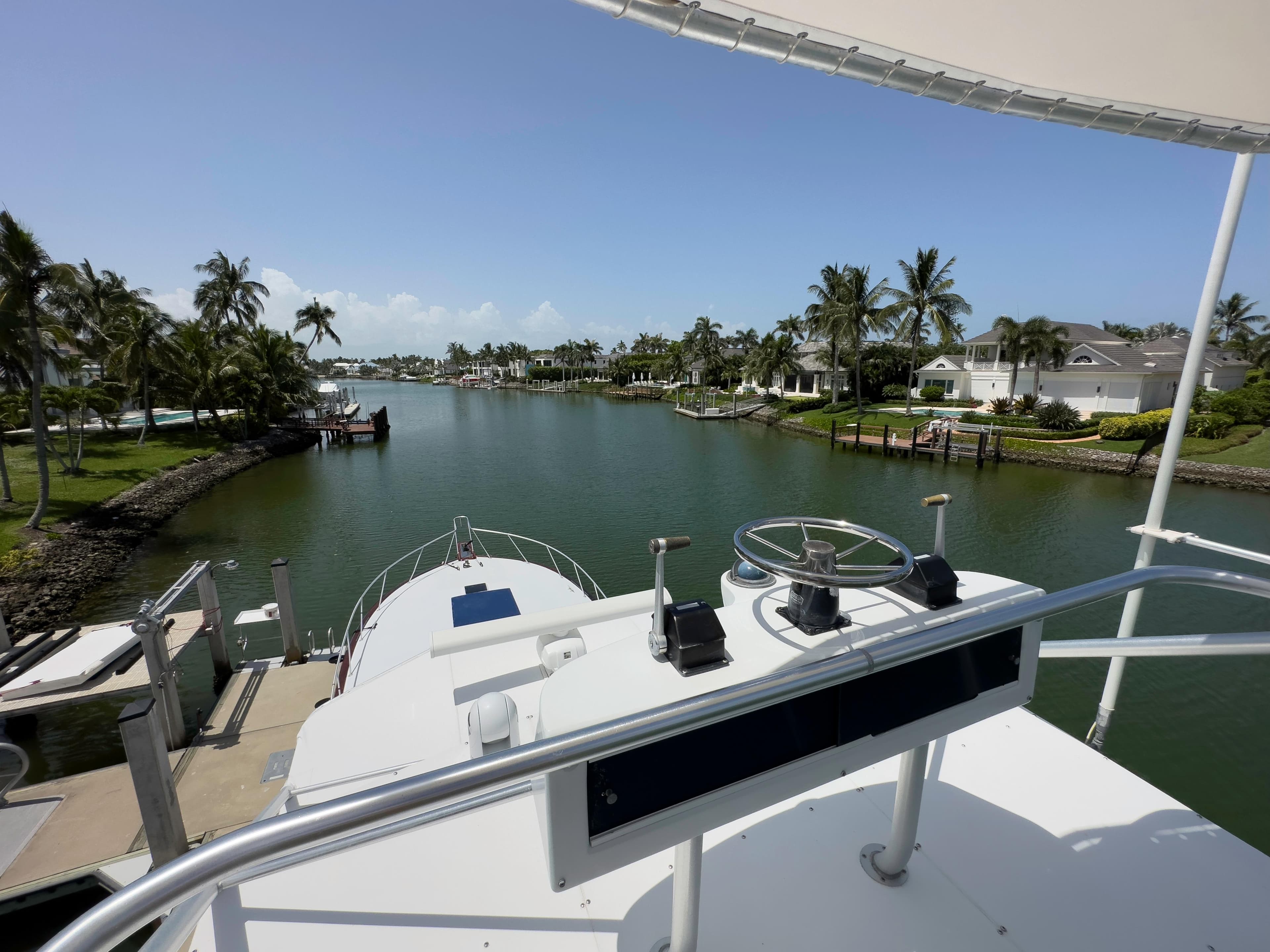 View from the helm of a 1990 Buddy Davis 61 Convertible yacht in a tropical marina.