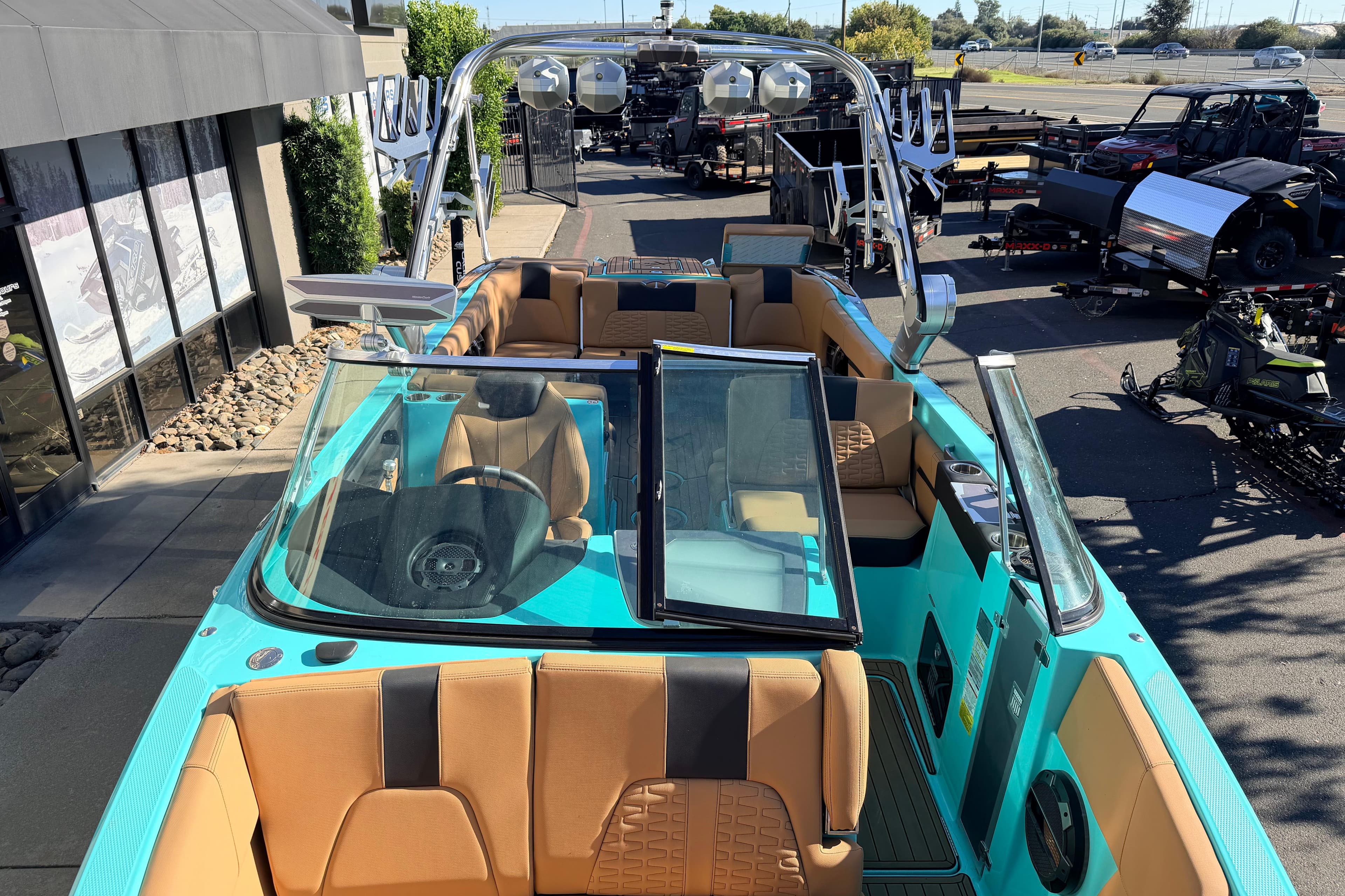 2021 MasterCraft X26 boat with turquoise exterior and tan interior, parked outdoors.