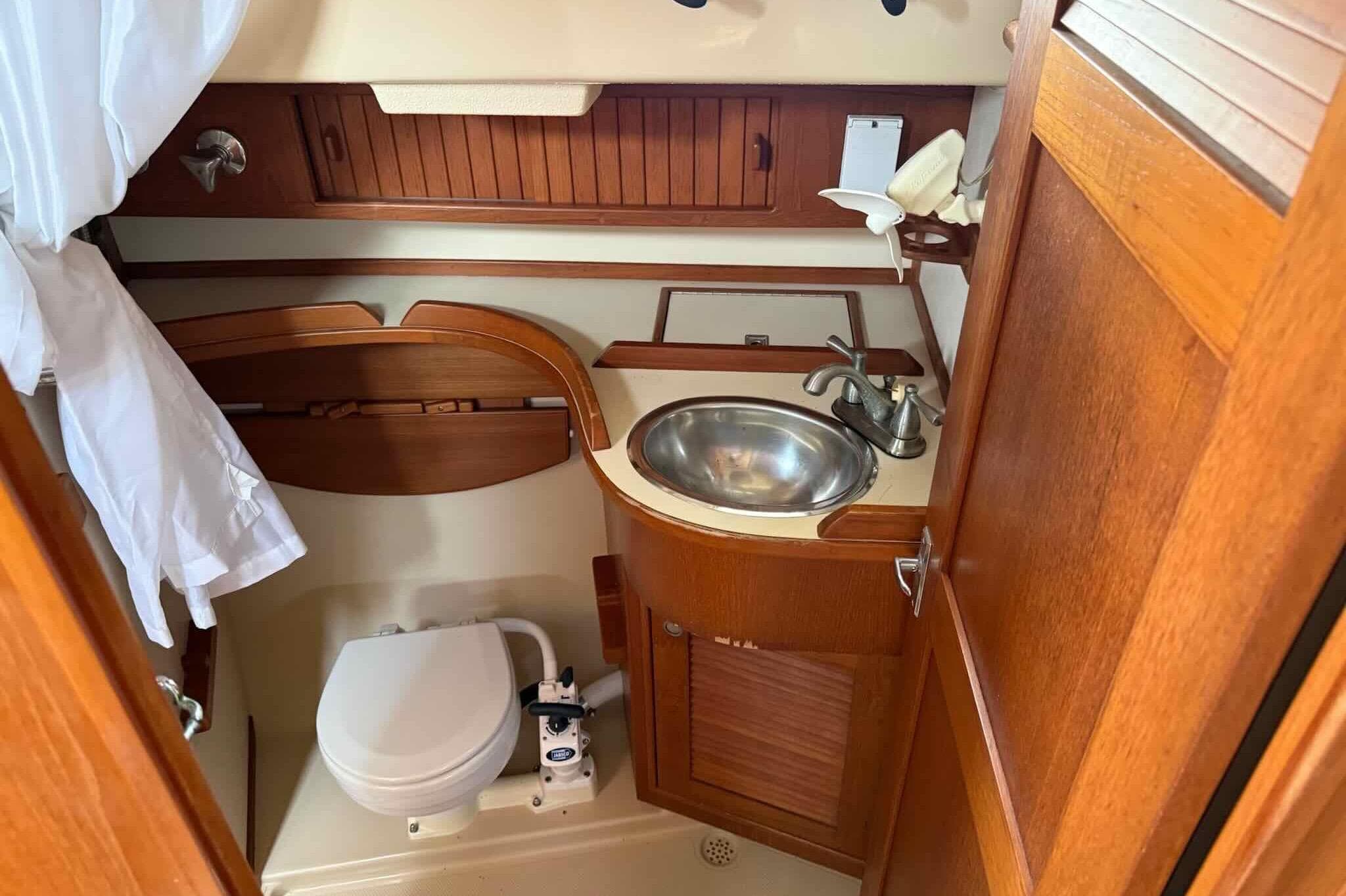 1998 Island Packet 40 yacht bathroom with wooden cabinetry and stainless steel sink.