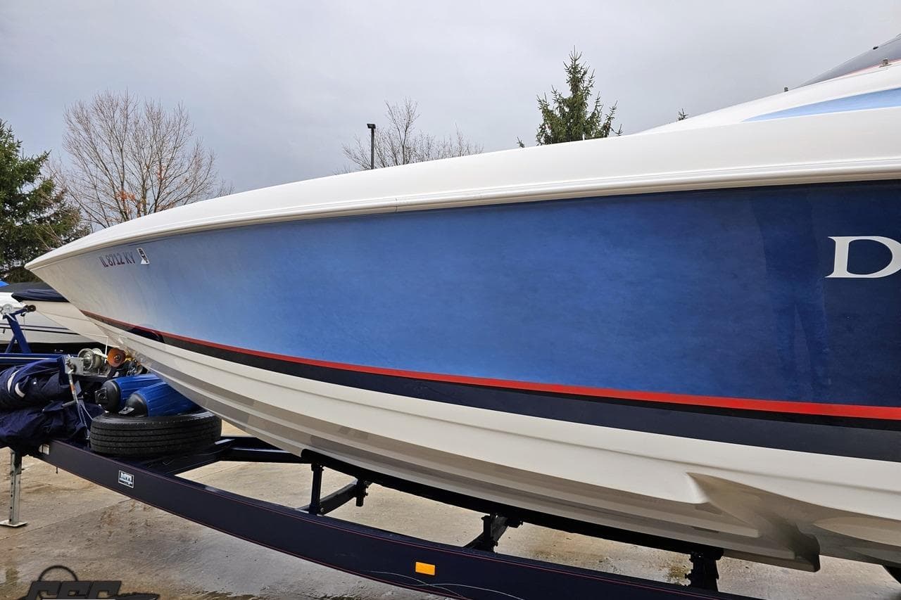 2000 Donzi 33 ZX boat on trailer, blue hull with red stripe, parked outdoors.