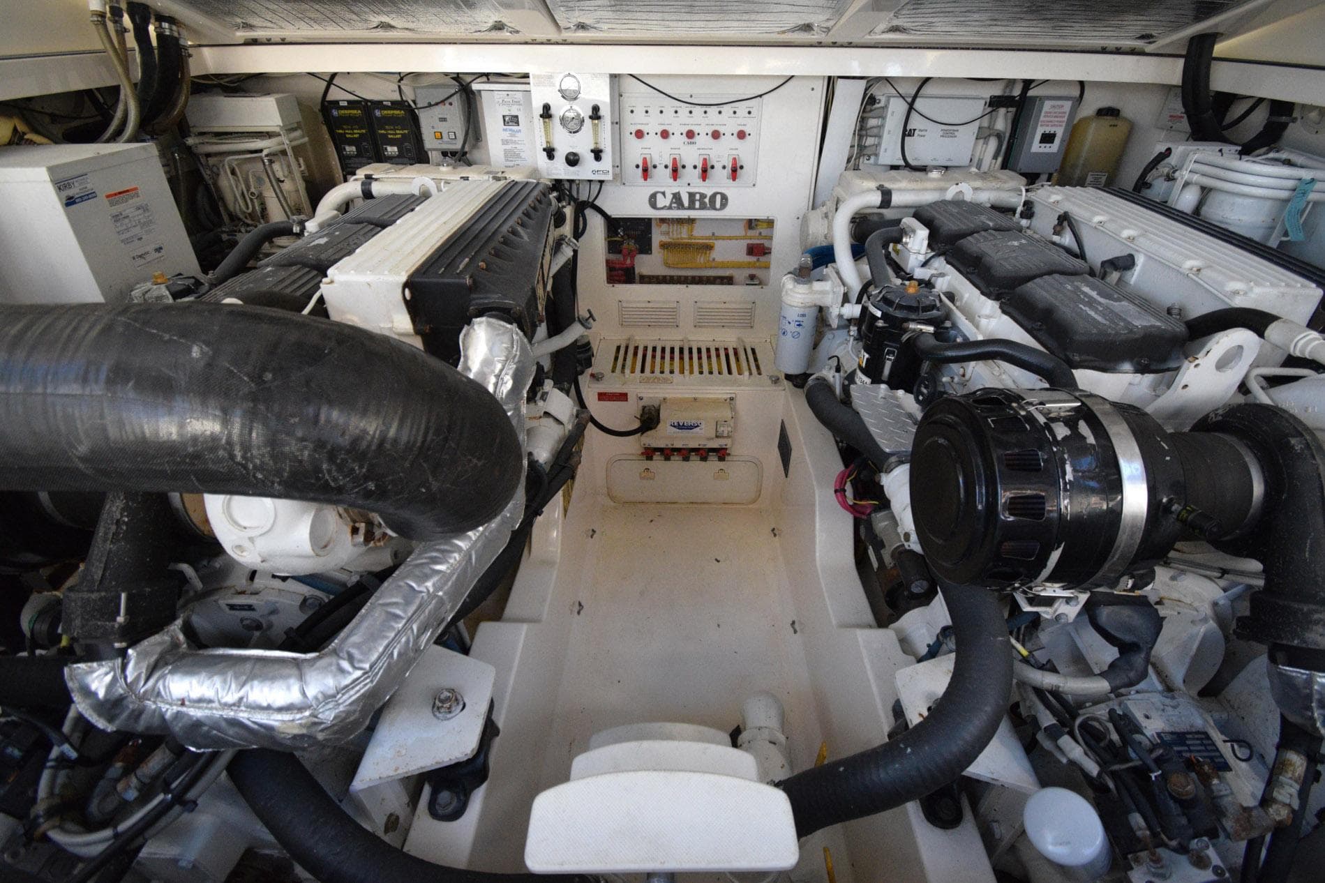 Engine room of a 2004 Cabo 40 Express boat, showcasing dual engines and control systems.
